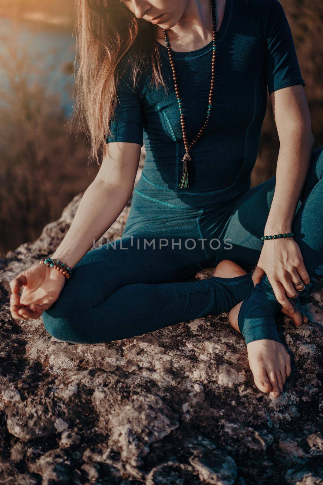 Yogi woman sitting in mala beads with gyan mudra, meditating, feeling free in front of wild nature. Mindful fitness coach having zen moment. Everyday yoga practice, calm breath, concentration.