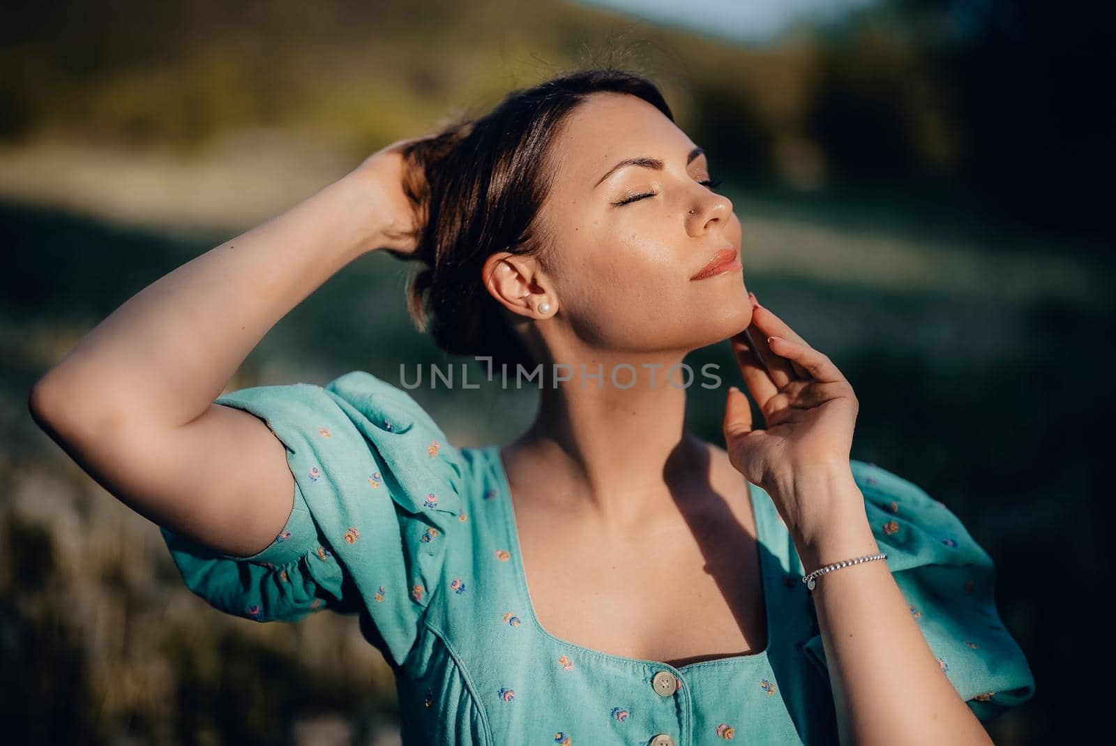 Portrait of young rural elegant woman posing on nature background. Sexy languid lady touching hair, enjoying summertime, sun rays. Vintage styled dress. High quality photo