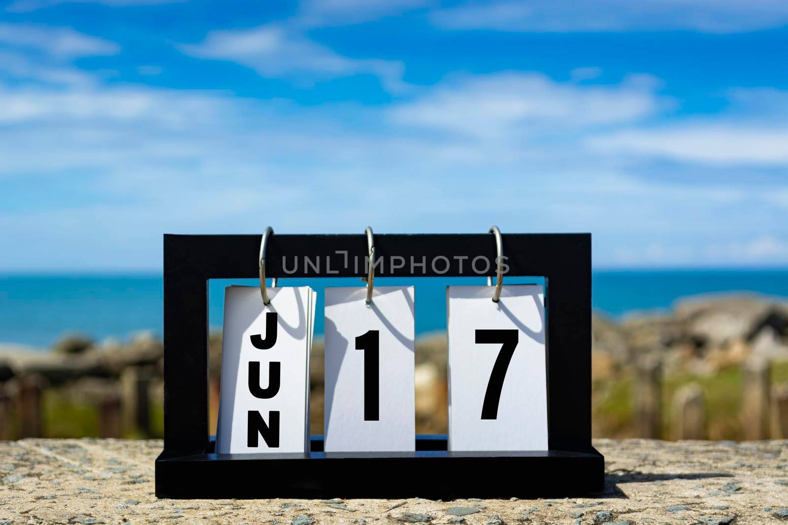 Jun 17 calendar date text on wooden frame with blurred background of ocean. Calendar date concept.