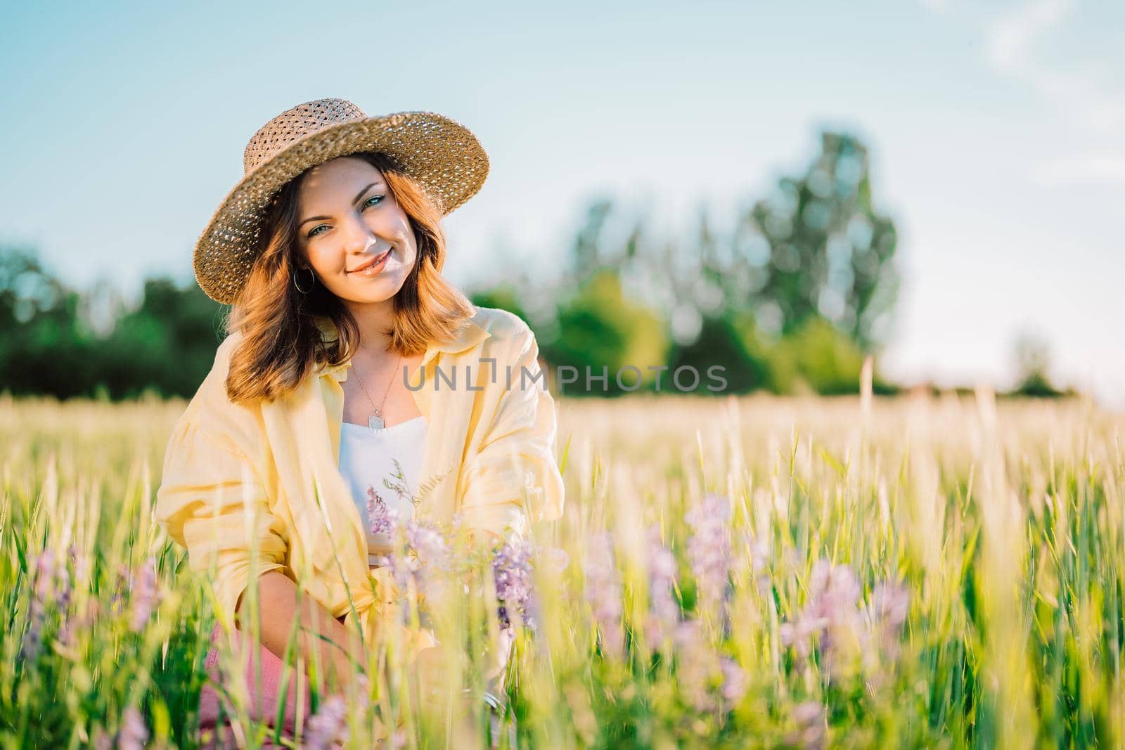 Portrait of rural stylish woman in straw hat posing in fresh wheat field. Grass background. Amazing nature, lifestyle, farmland, growing cereal plants. High quality photo