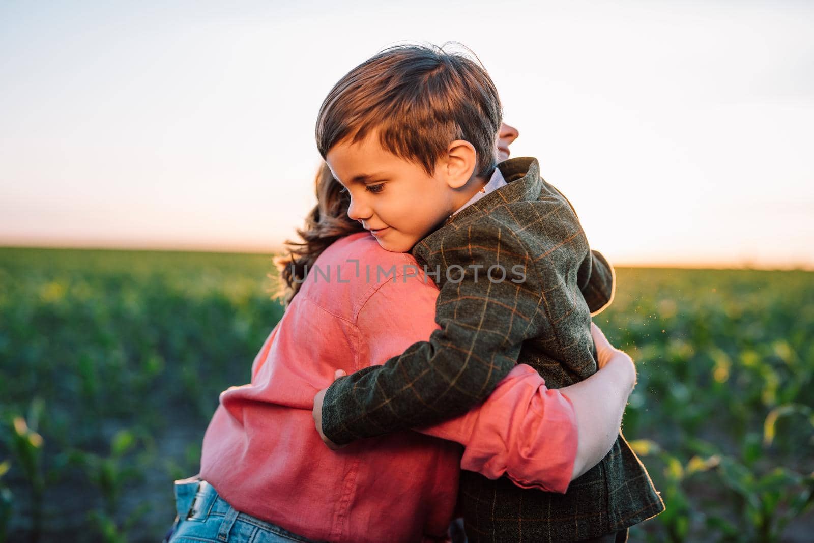 Loving smiling son hugs mom tightly. Tender family scene. Cute 3 year old ukrainian kid with mother. Parenthood, childhood, happiness, children wellbeing concept. by kristina_kokhanova