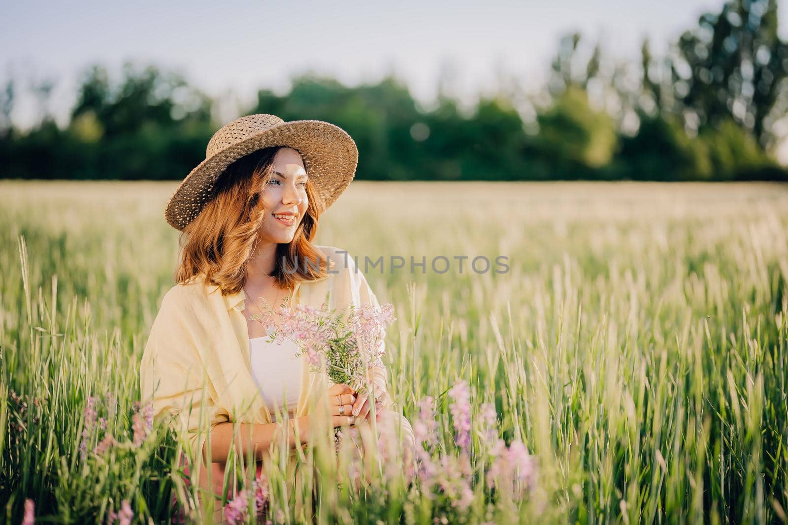 Portrait of rural stylish woman in straw hat posing in fresh wheat field. Grass background. Amazing nature, lifestyle, farmland, growing cereal plants. High quality photo