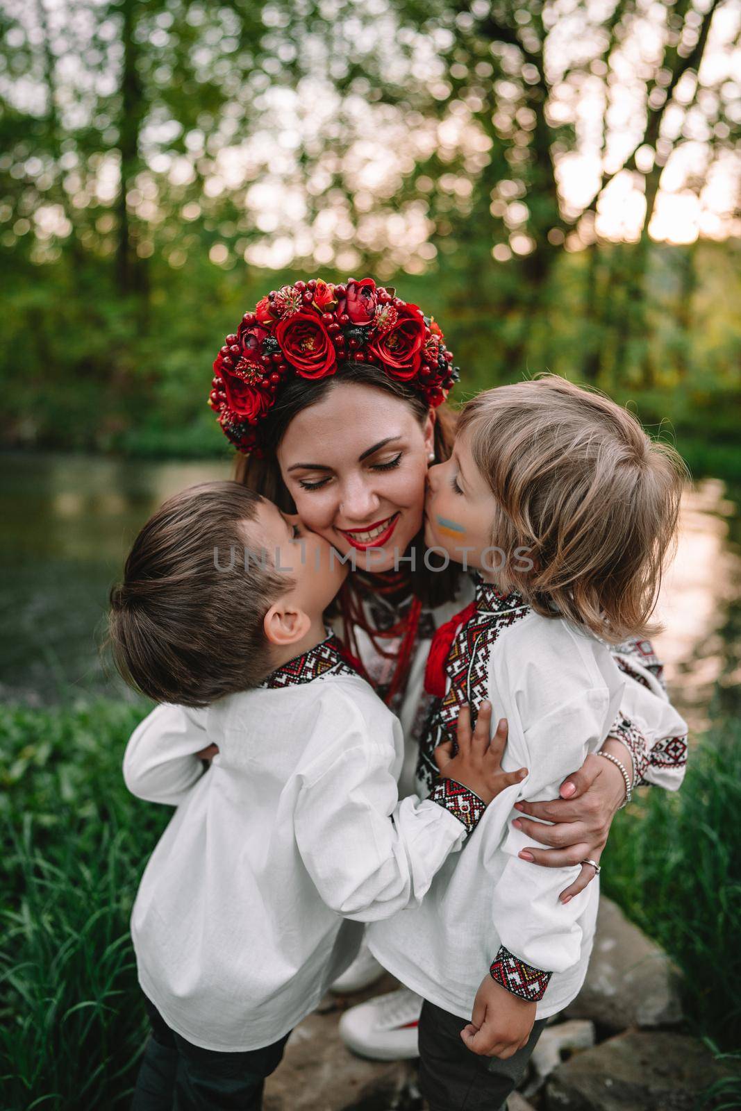 Little ukrainian boys kissing mother on cheeks. Happy family in traditional embroidery vyshyvanka shirts. Ukraine, brothers, sons, freedom, national costume. by kristina_kokhanova
