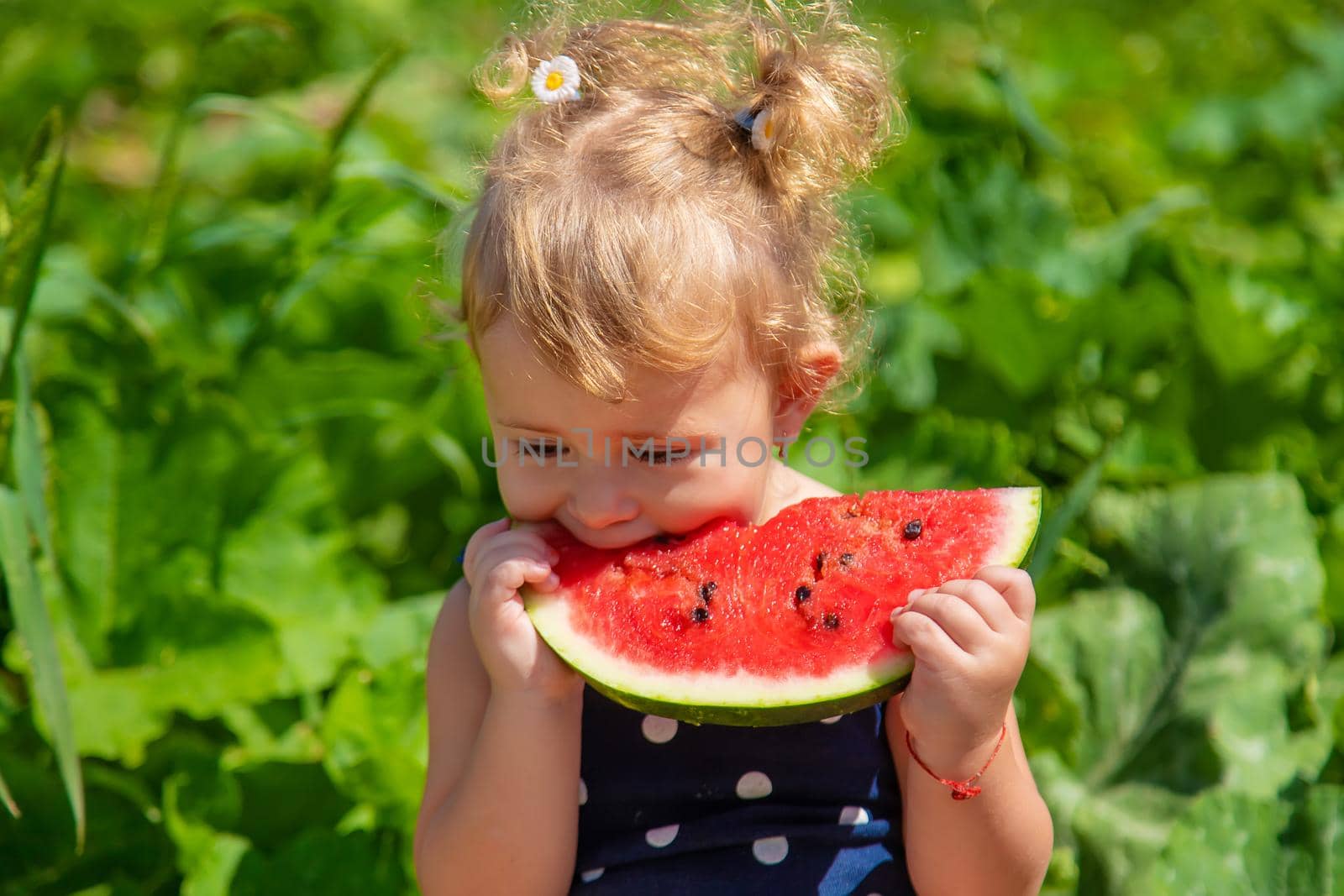 A child eats watermelon in the park. Selective focus. Kid.