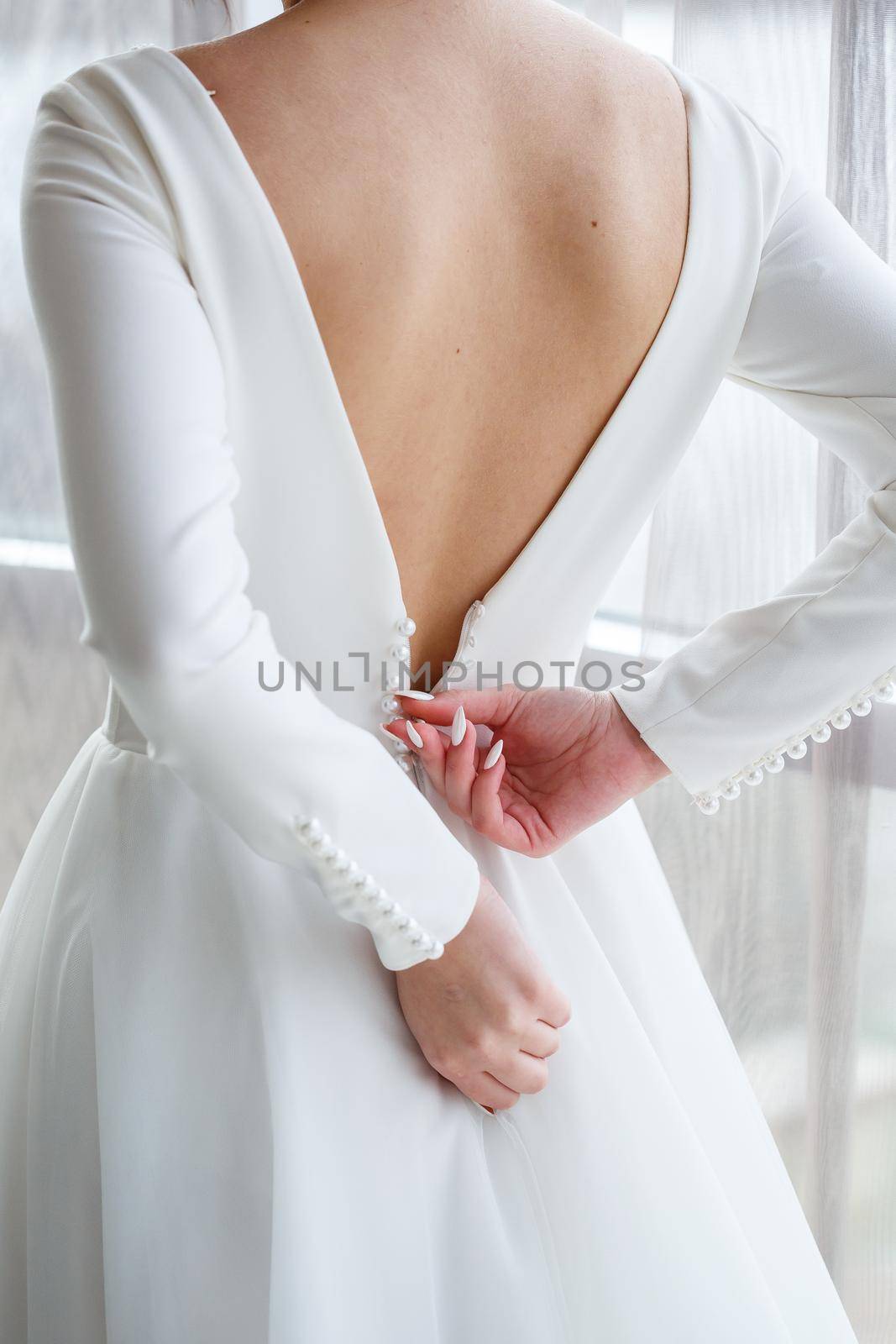 Bride zips zipper on her wedding white dress by Dmitrytph