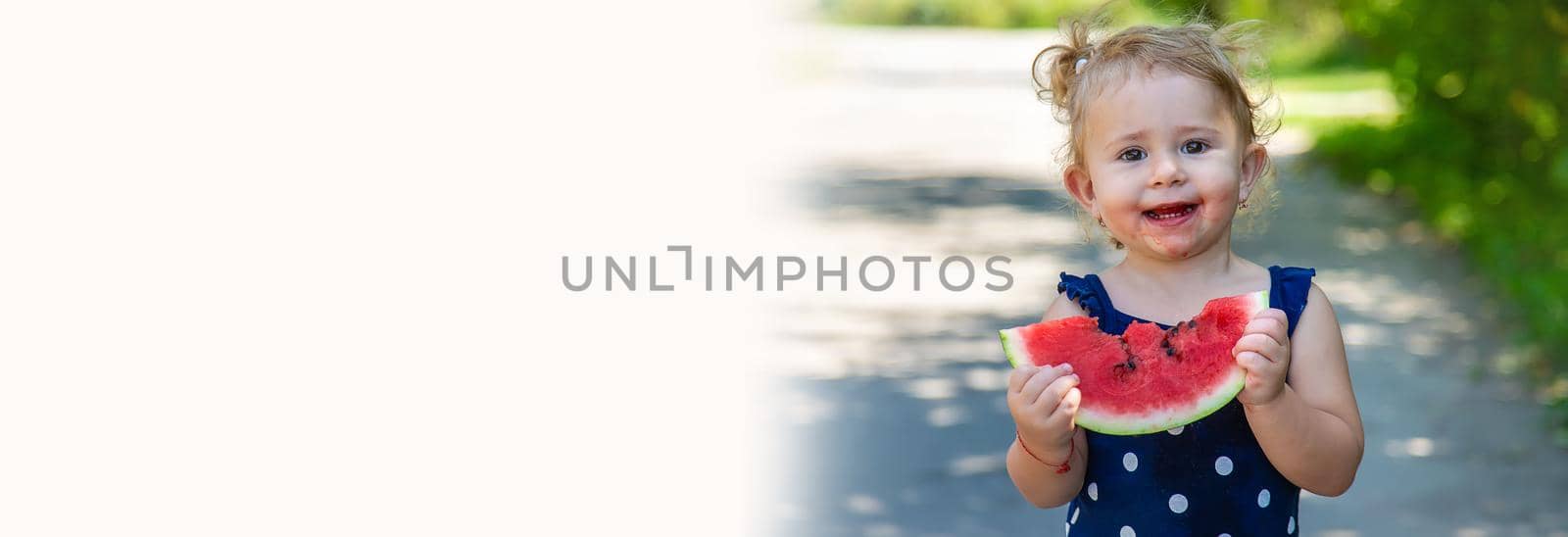 A child eats watermelon in the park. Selective focus. by yanadjana