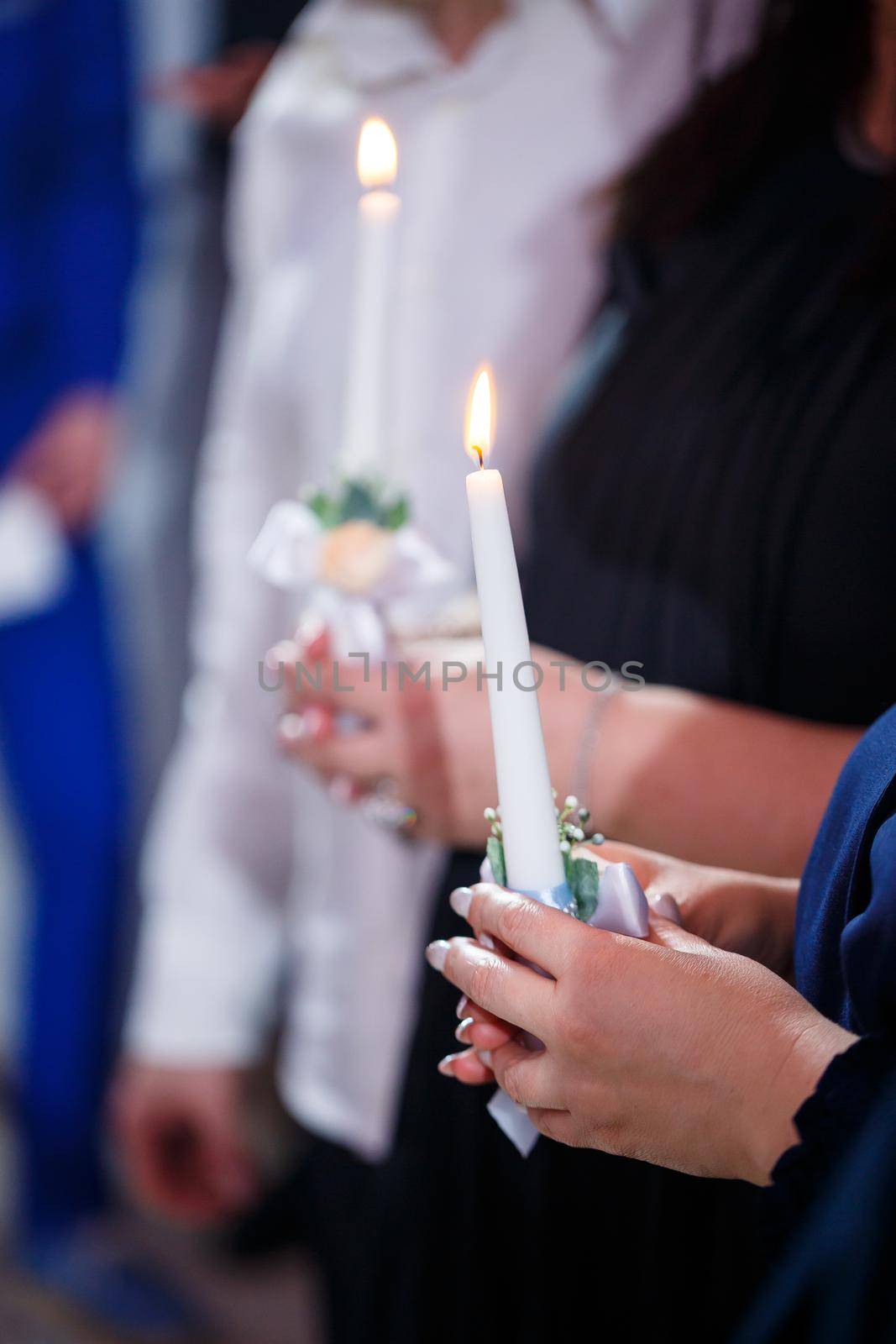 Burning candle in the hands of the newlyweds