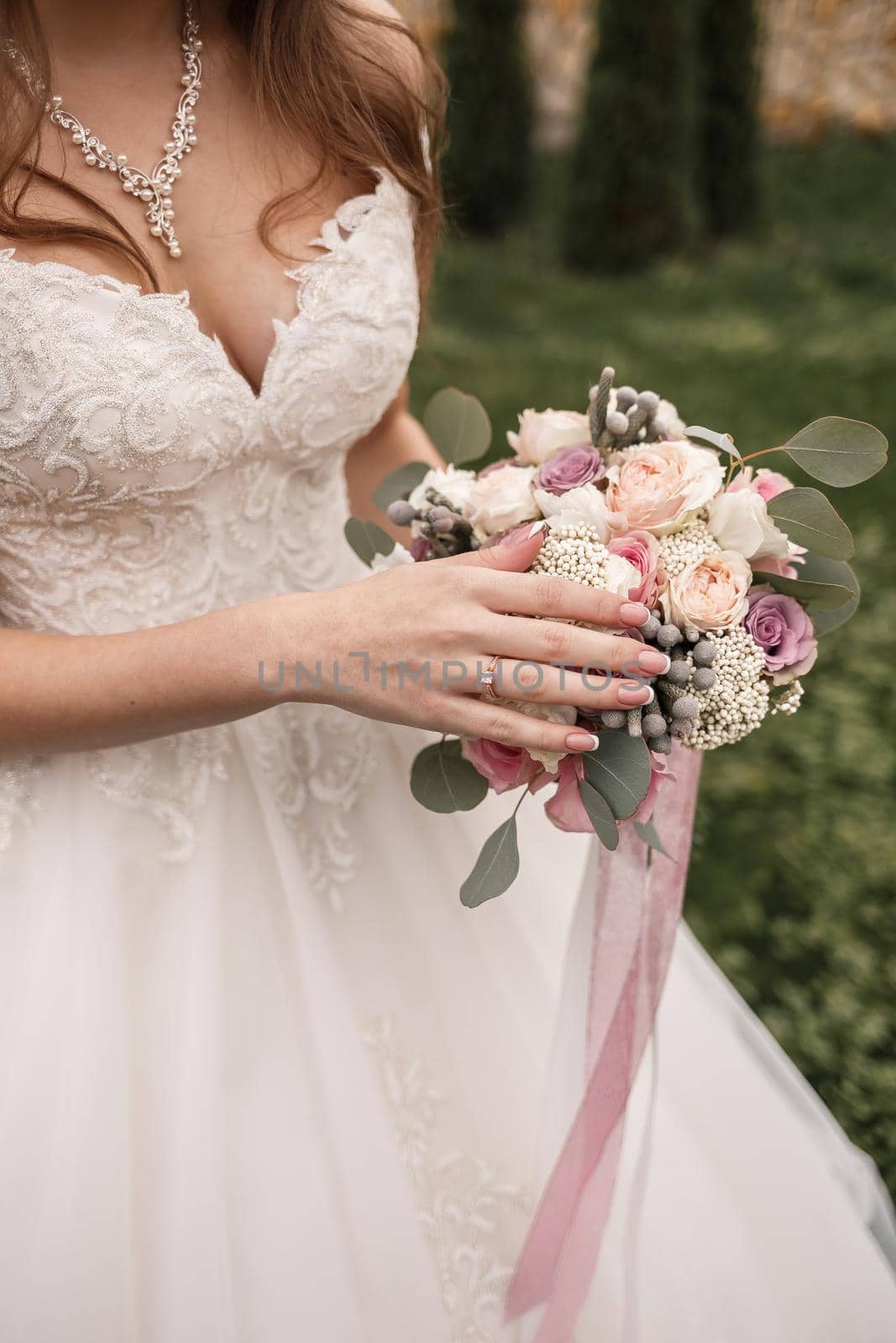 Beautiful bride holding a delicate bouquet of flowers in her hands on a wedding day