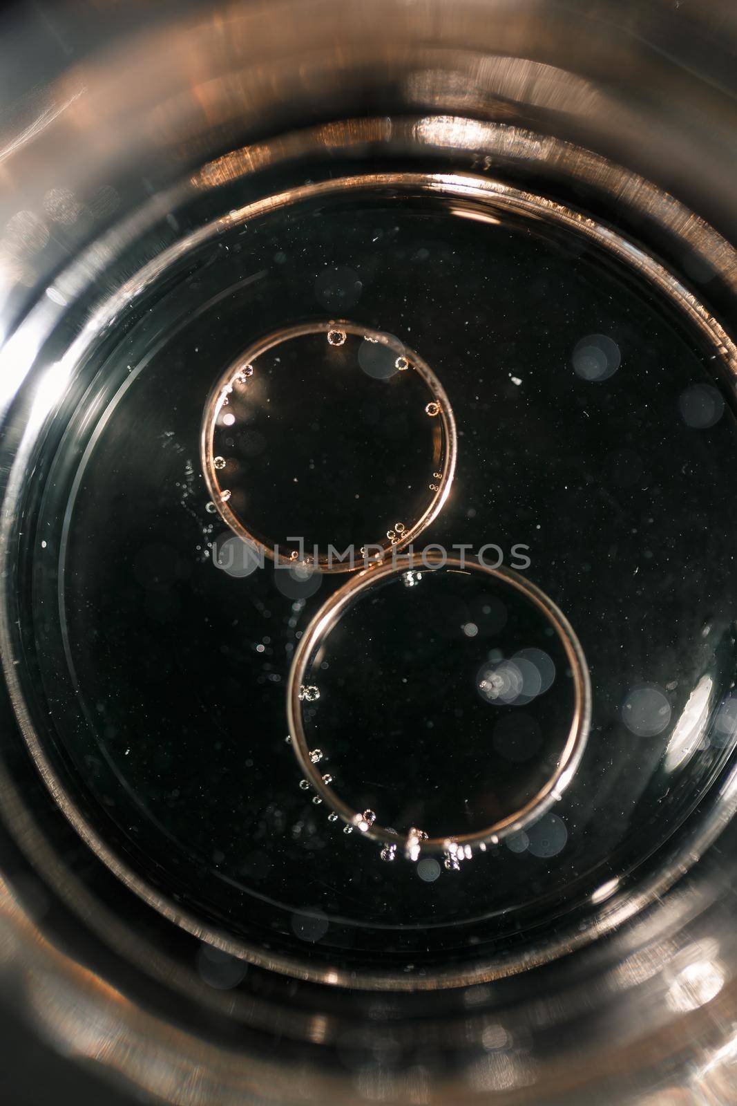 Gold precious wedding rings in a glass of sparkling champagne