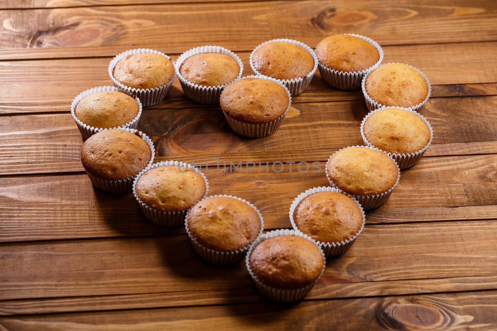 Homemade muffins in paper wrap on wooden board