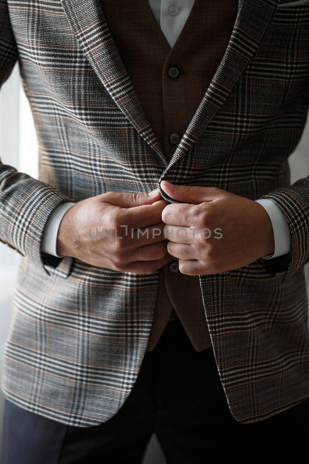 Stylish man groom buttoning a button on his jacket