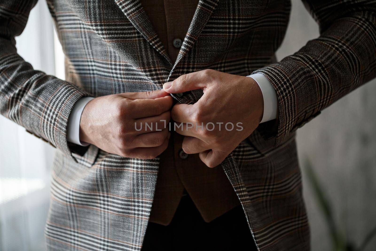 Stylish man groom buttoning a button on his jacket