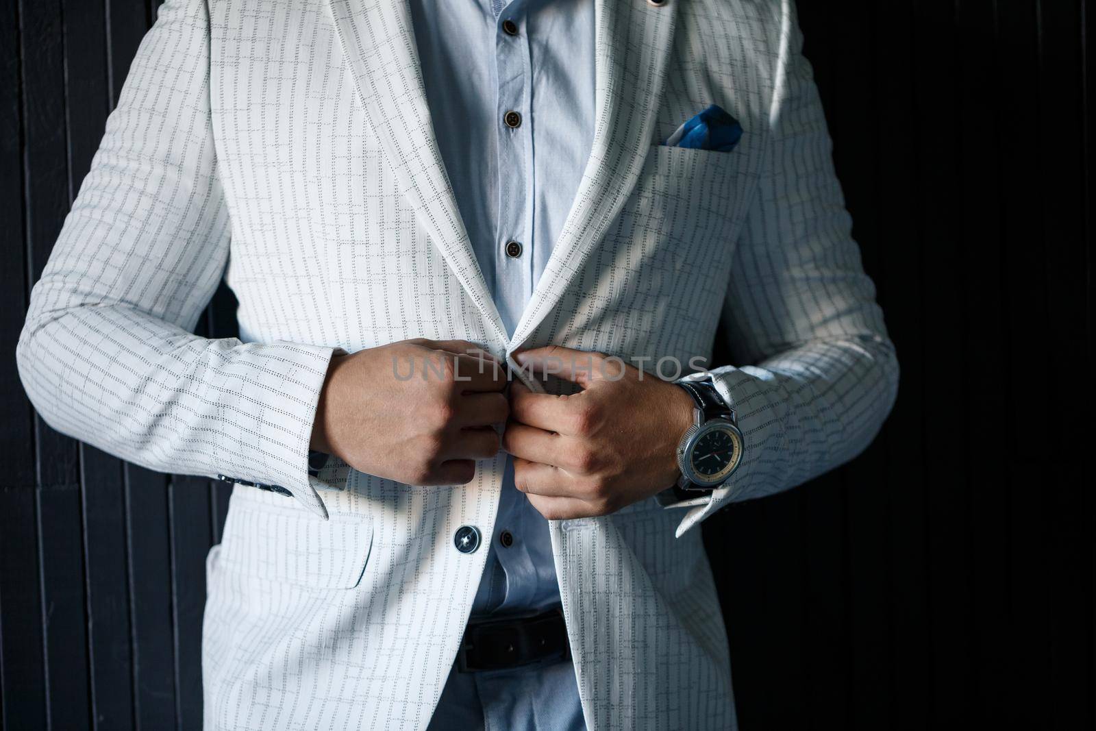 Stylish man groom buttoning a button on his jacket