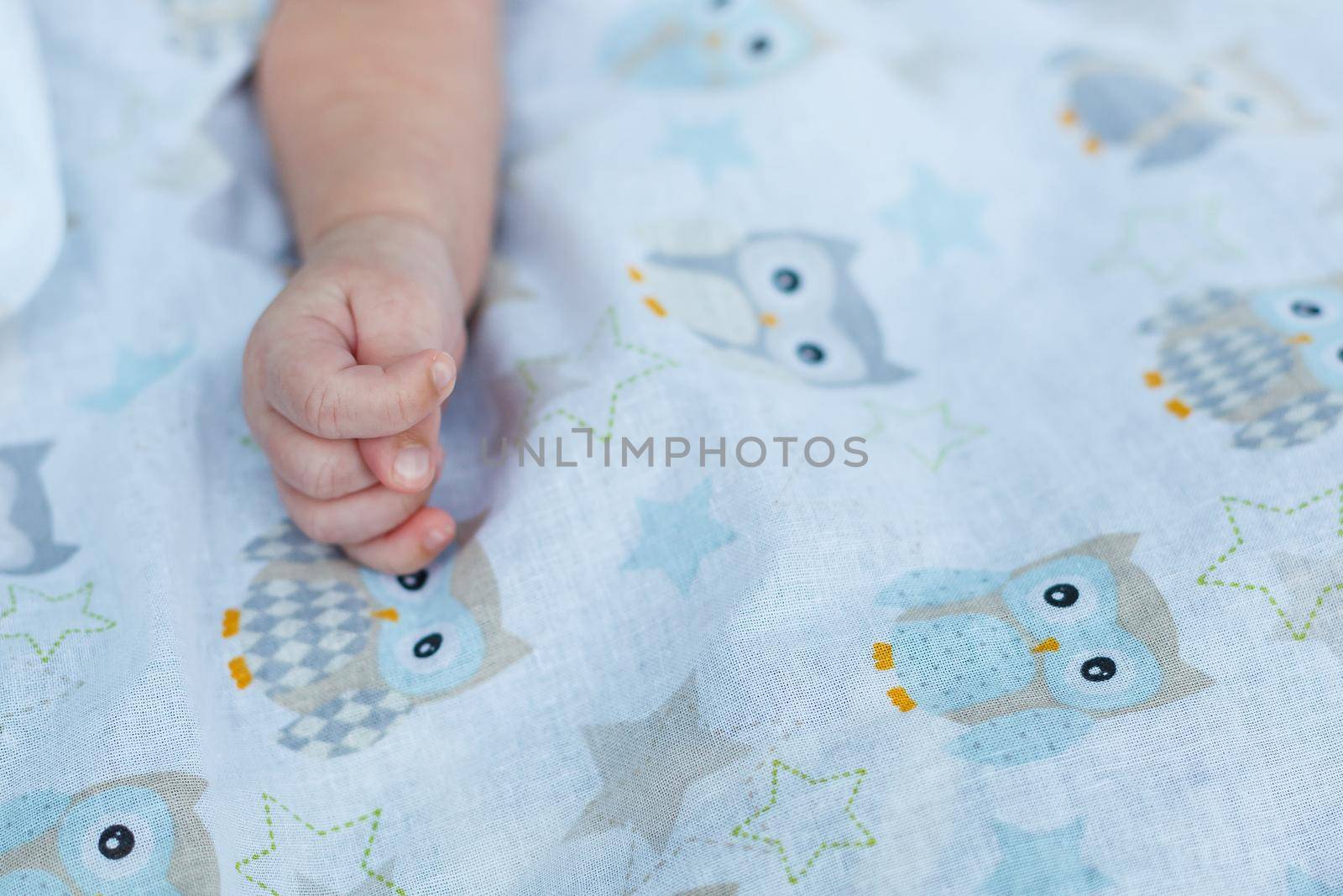Baby hand on a white coverlet by Dmitrytph