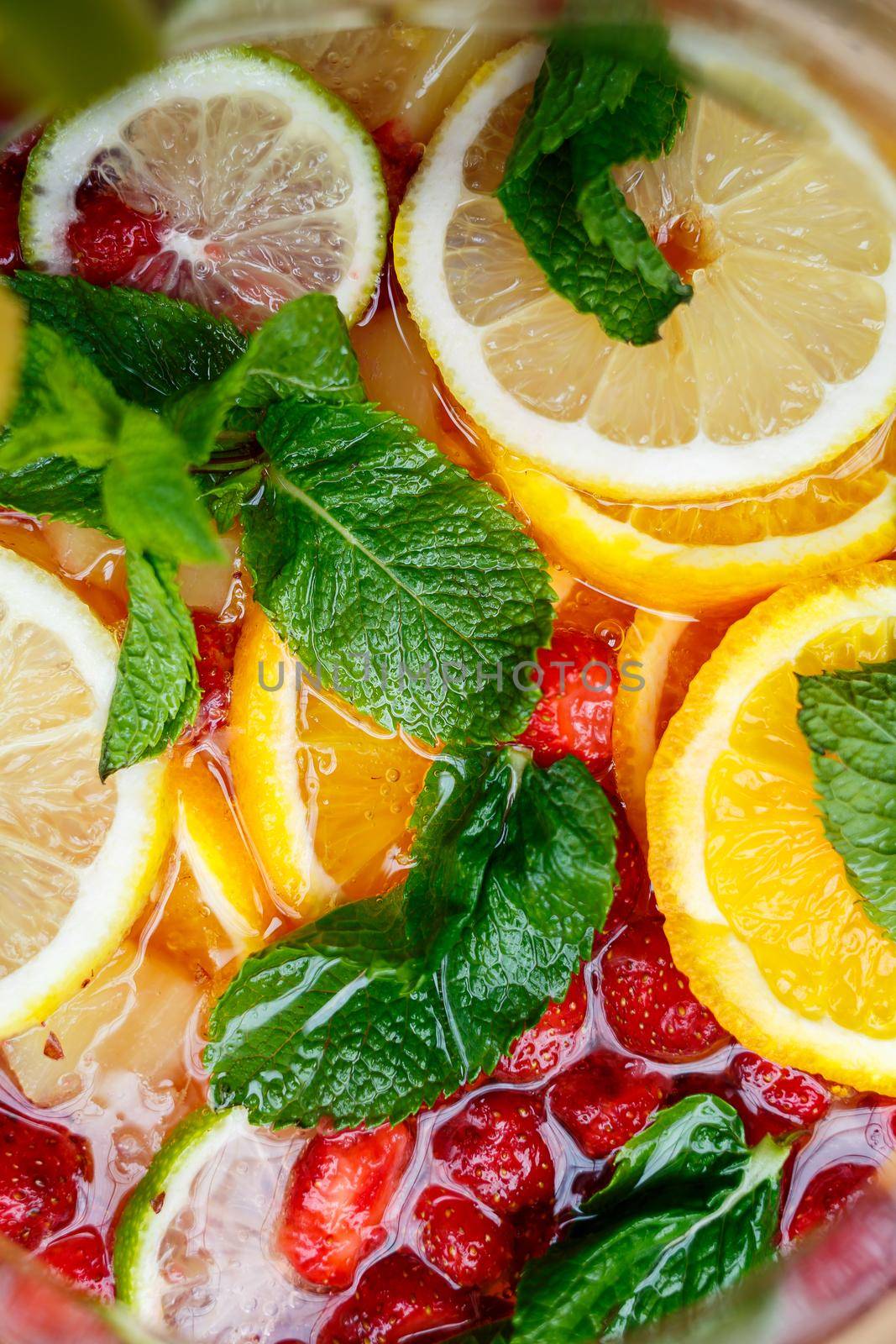 Refreshing lemonade with fresh fruit orange lemon cherry and mint leaves. Delicious non-alcoholic fruit cocktail in a jug