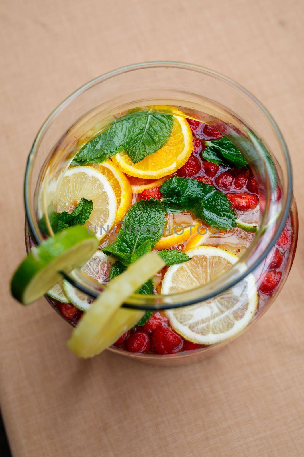 Refreshing lemonade with fresh fruit orange lemon cherry and mint leaves. Delicious non-alcoholic fruit cocktail in a jug