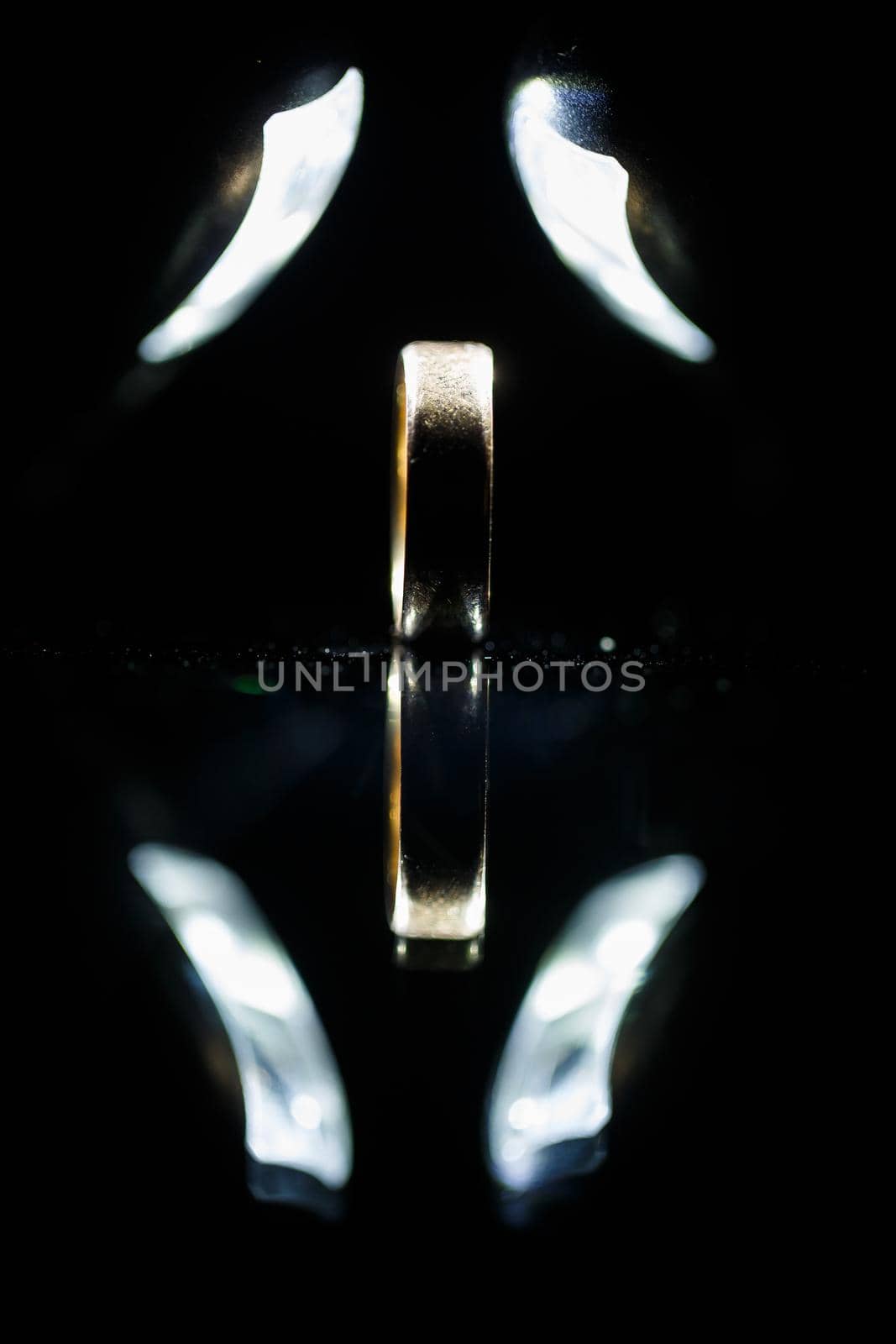 Gold wedding ring on black glass