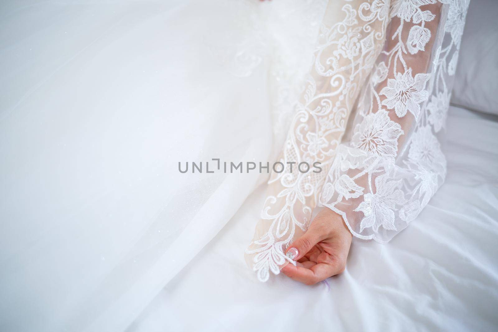 The bride holds a white dress in her hands on the wedding day.