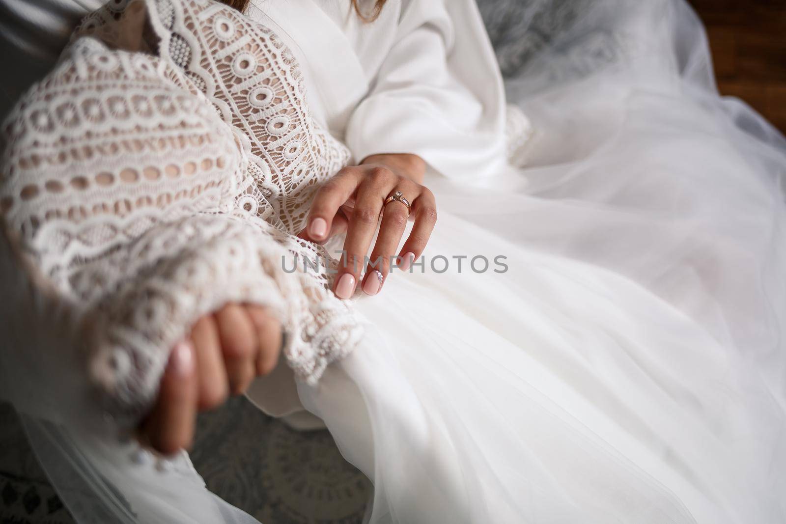 The bride holds a white dress in her hands on the wedding day.