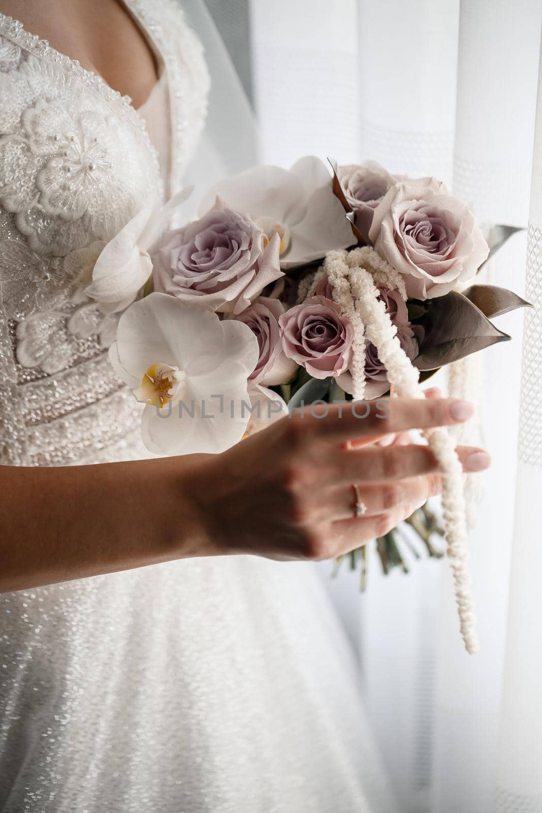 Beautiful bride holding a delicate bouquet of flowers in her hands on a wedding day