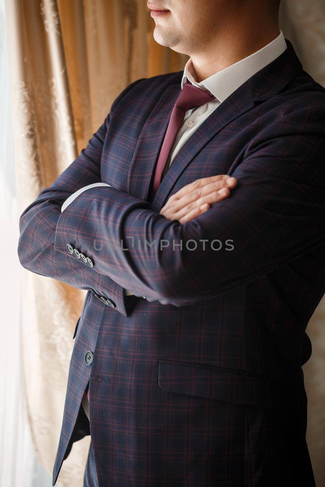 Stylish man groom buttoning a button on his jacket