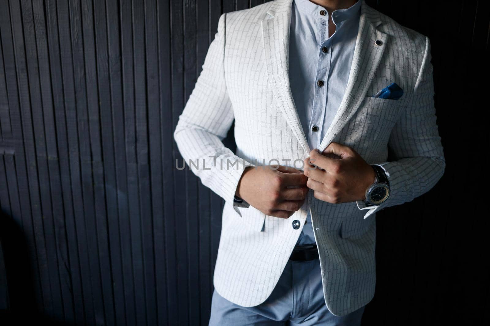 Stylish man groom buttoning a button on his jacket