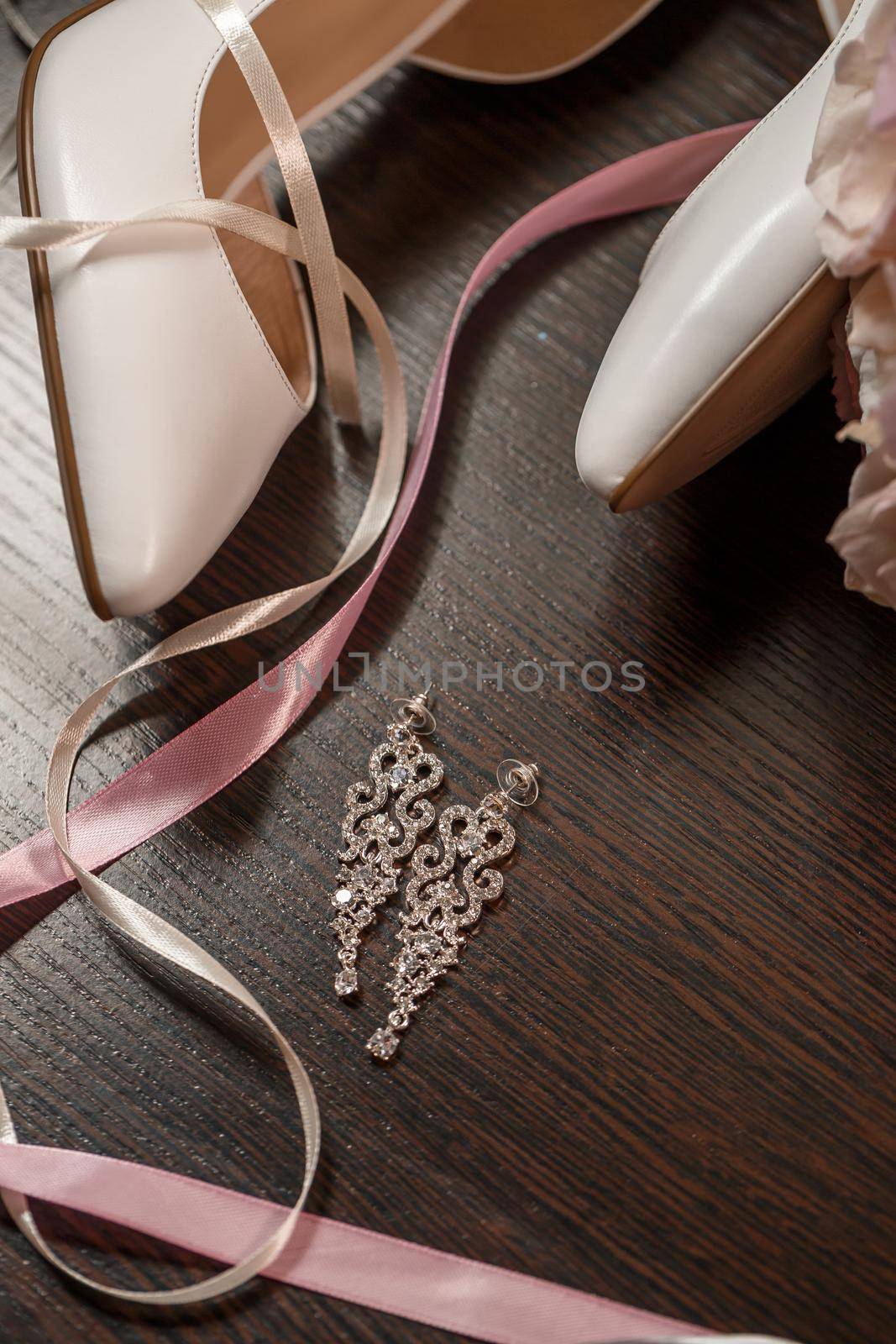 Wedding shoes for the bride. White high-heeled shoes near wedding rings, wedding jewelry. Marriage concept