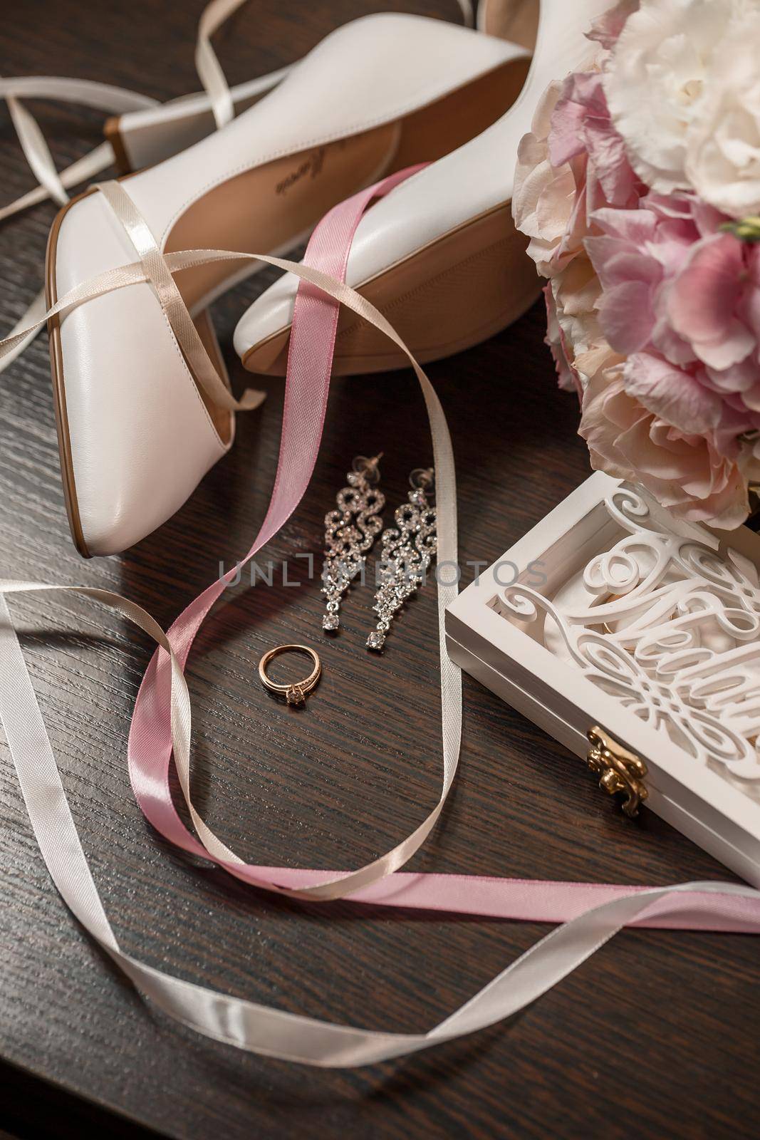 Wedding shoes for the bride. White high-heeled shoes near wedding rings, wedding jewelry. Marriage concept