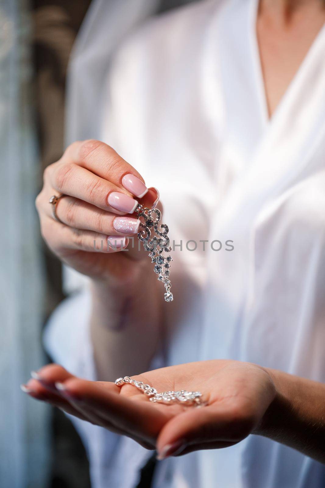 The bride holds earrings in her hand on her wedding day. Jewelry for a holiday for the newlyweds
