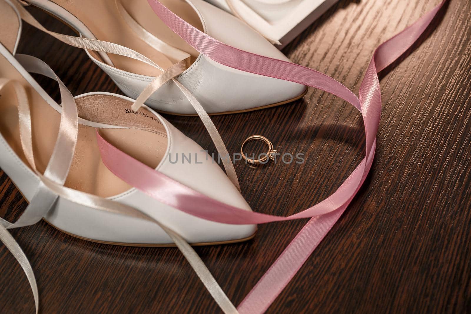 Wedding shoes for the bride. White high-heeled shoes near wedding rings, wedding jewelry. Marriage concept