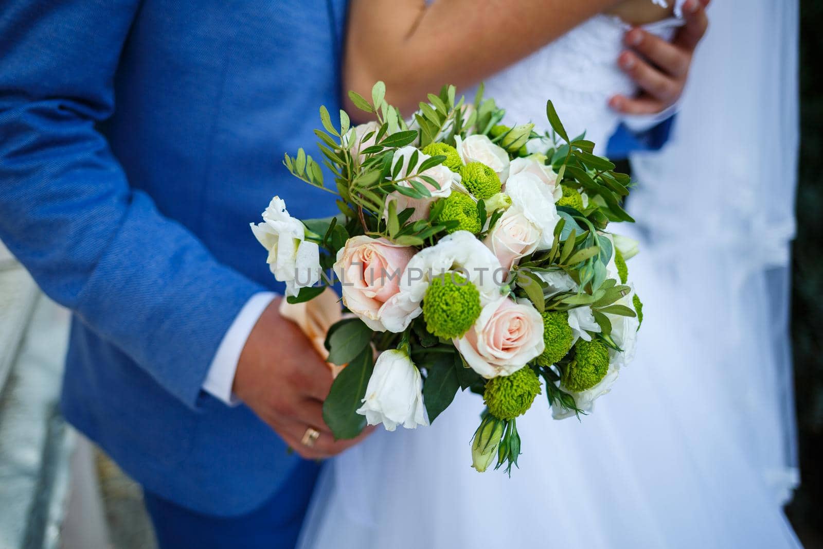Beautiful wedding bouquet of flowers in the hands of the newlyweds