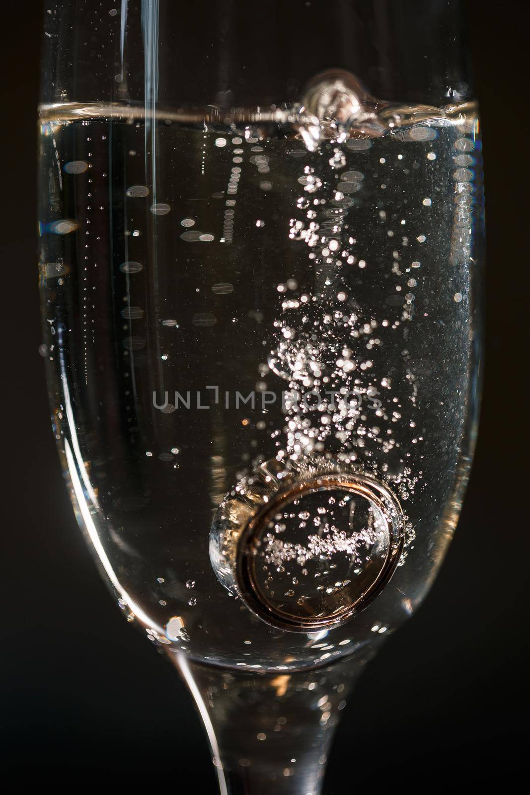 Gold precious wedding rings in a glass of sparkling champagne
