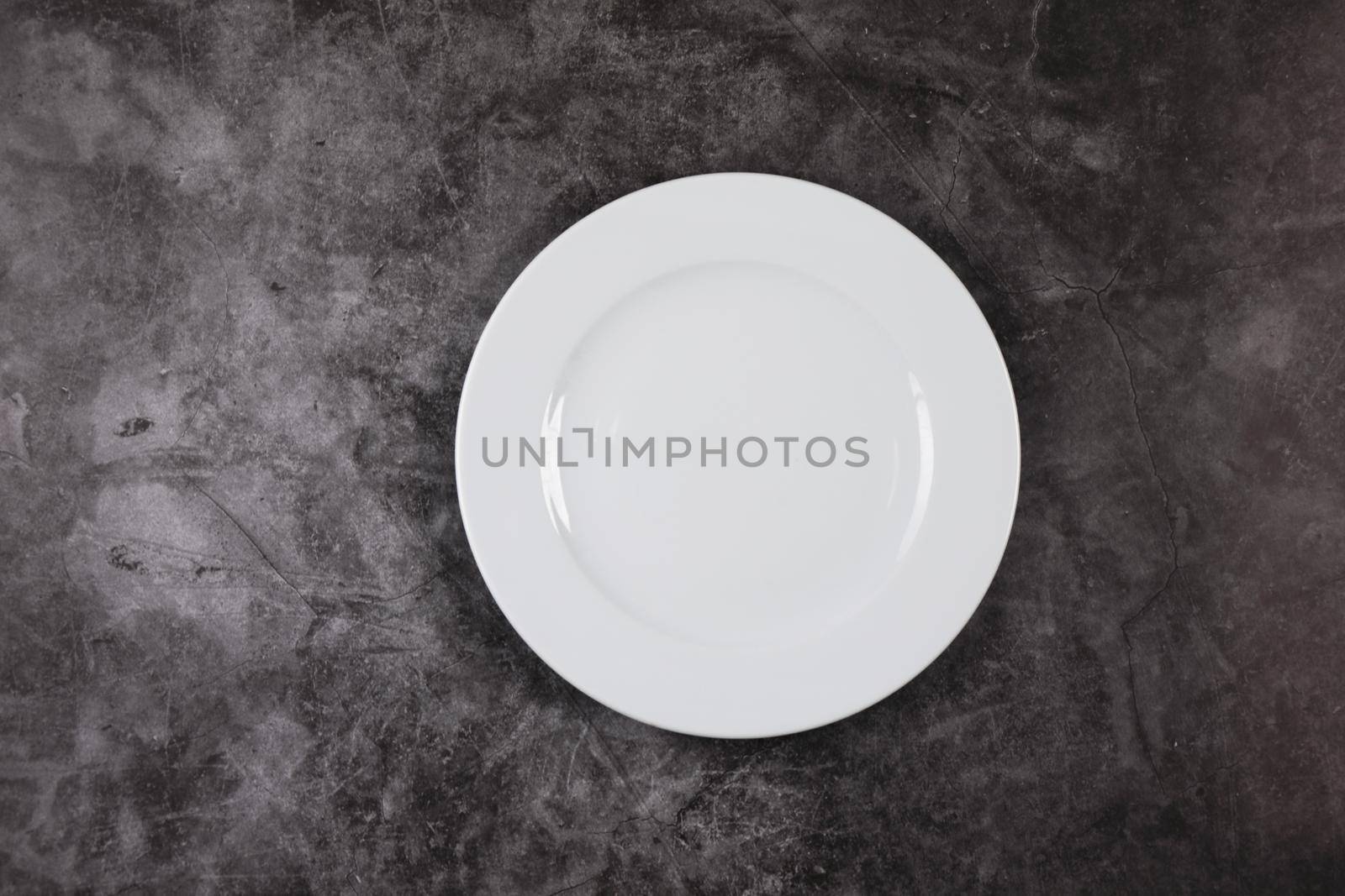 A white dinner plate on a grey and white marble surface