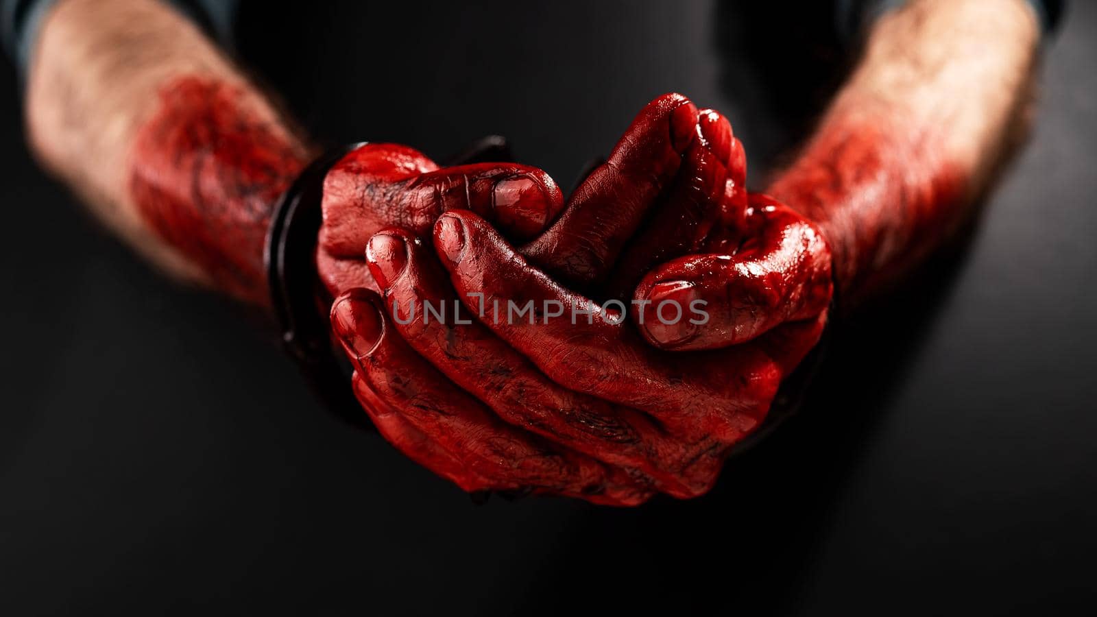 Close-up of male bloody handcuffed hands on a black background