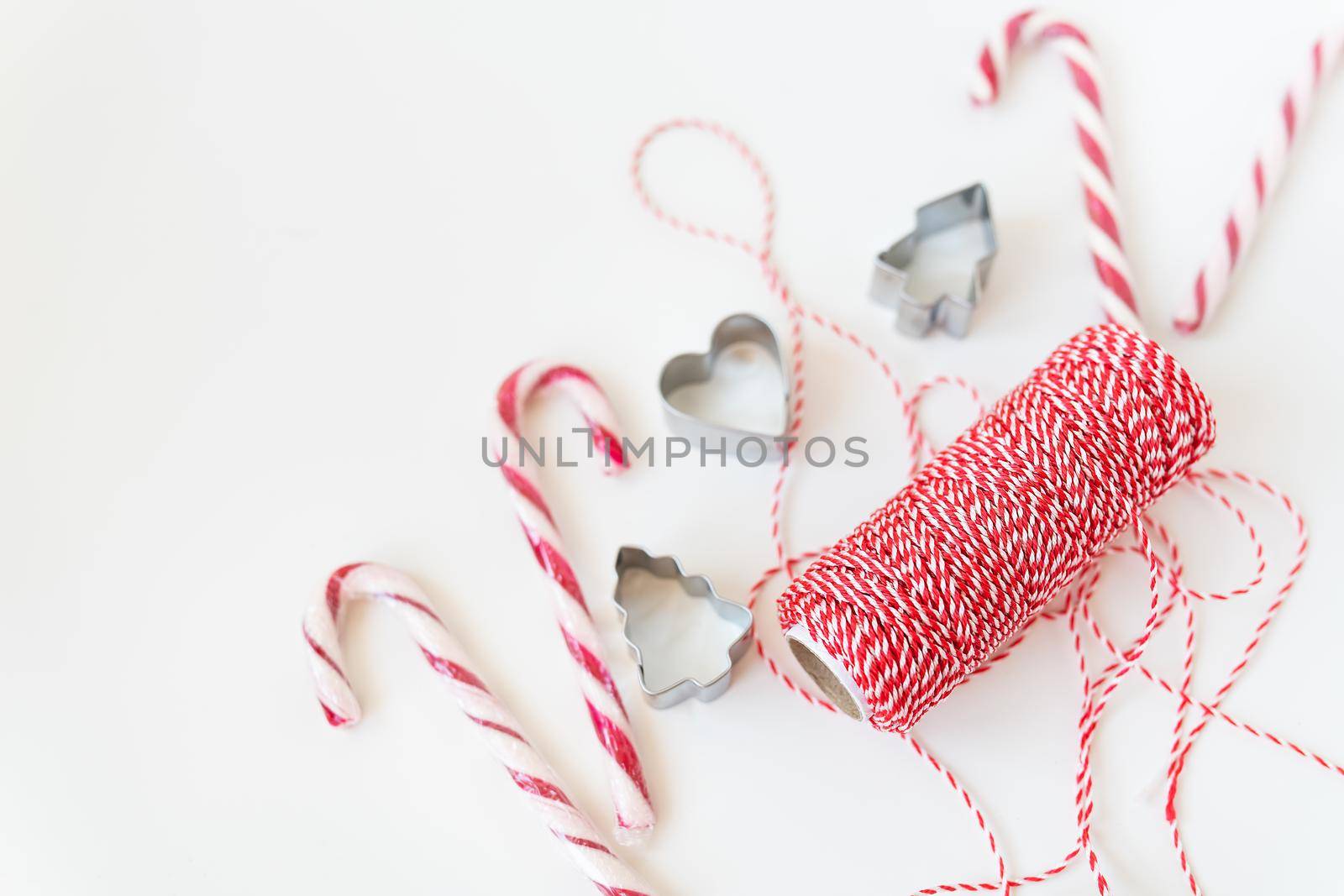 Christmas candies, along with cookie cutters, red thread for wrapping gifts, lie on a white table. Christmas and New Year's Eve 2023-2024. by sfinks