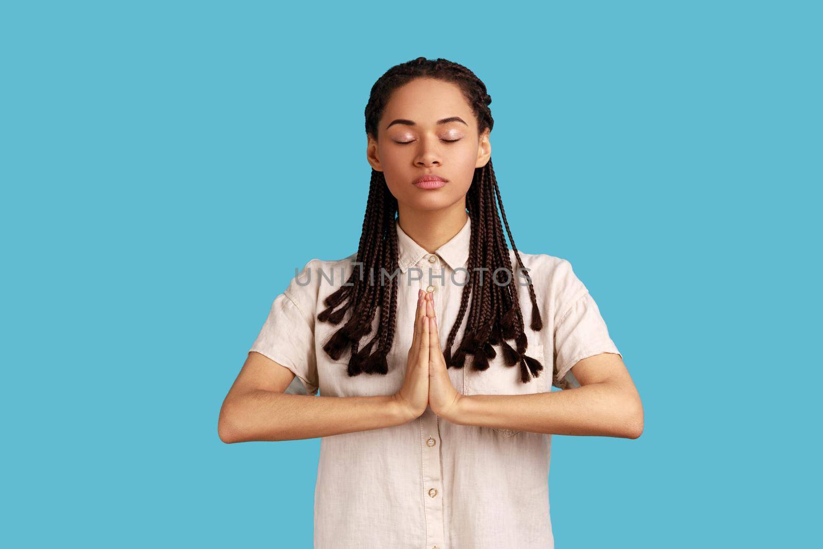 Woman keeps hands in yoga gesture, has calm facial expression, keeping palms pressed together. by Khosro1