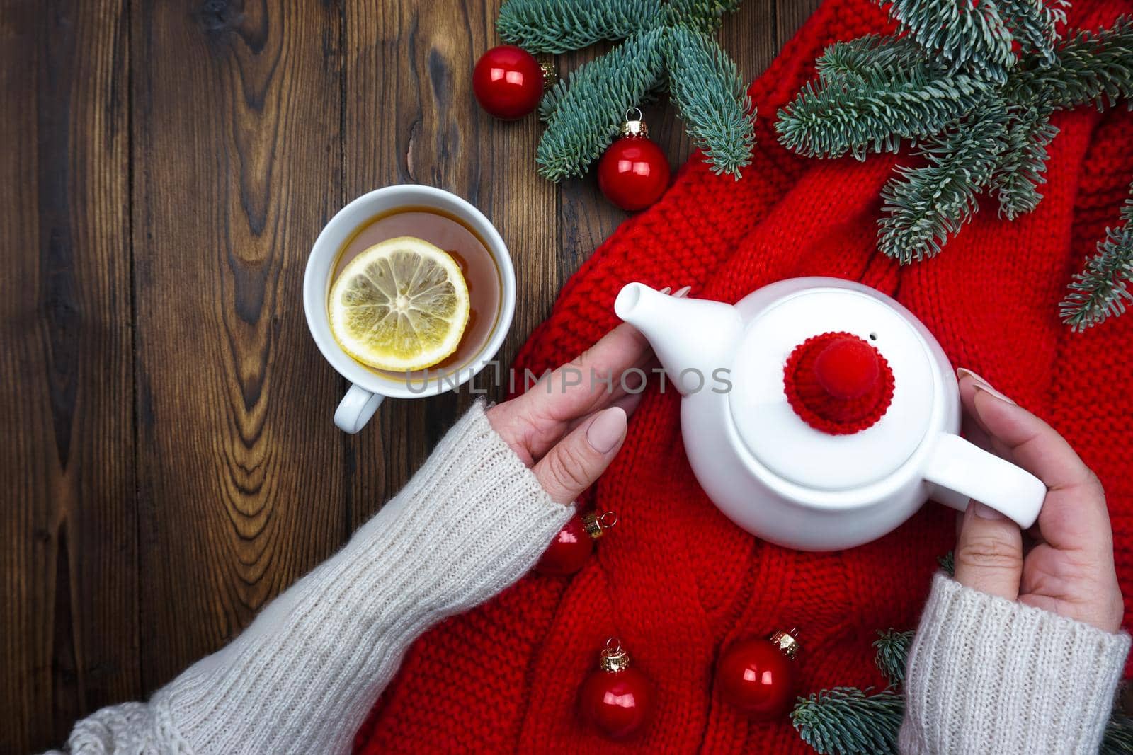 A mug of hot tea with lemon is in women's hands by Spirina