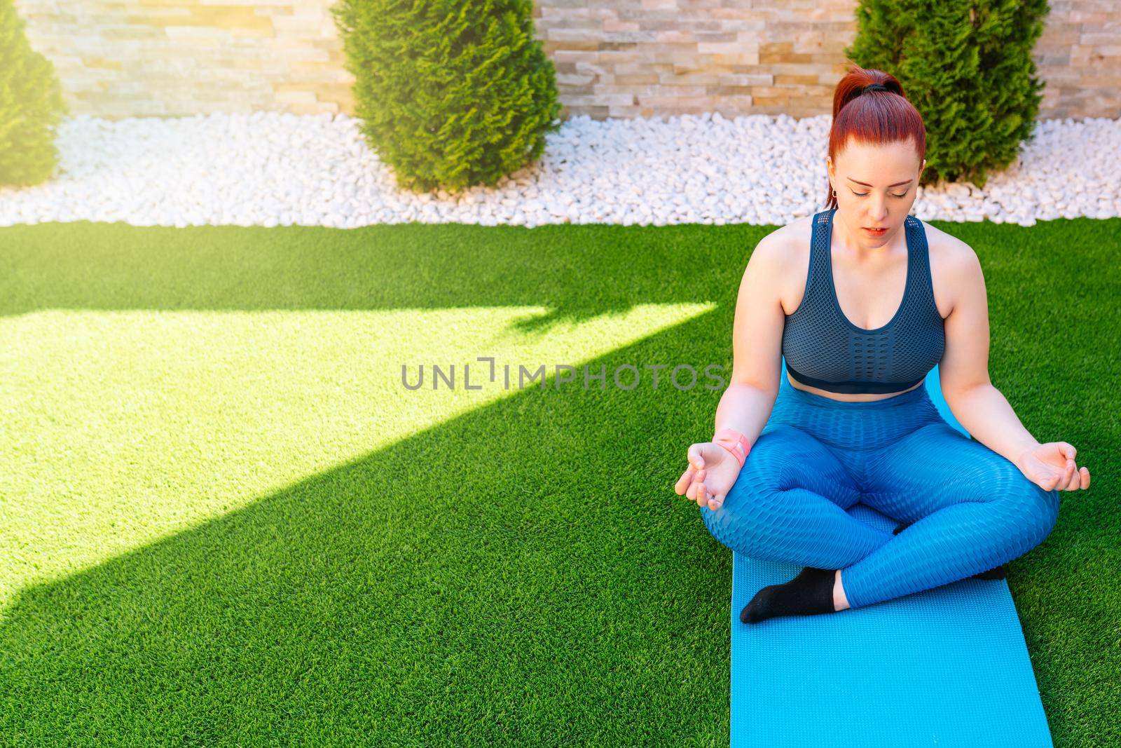 woman practicing meditation in the open air, relaxation exercises, doing the lotus posture. copy space. concept of health and well-being. by CatPhotography