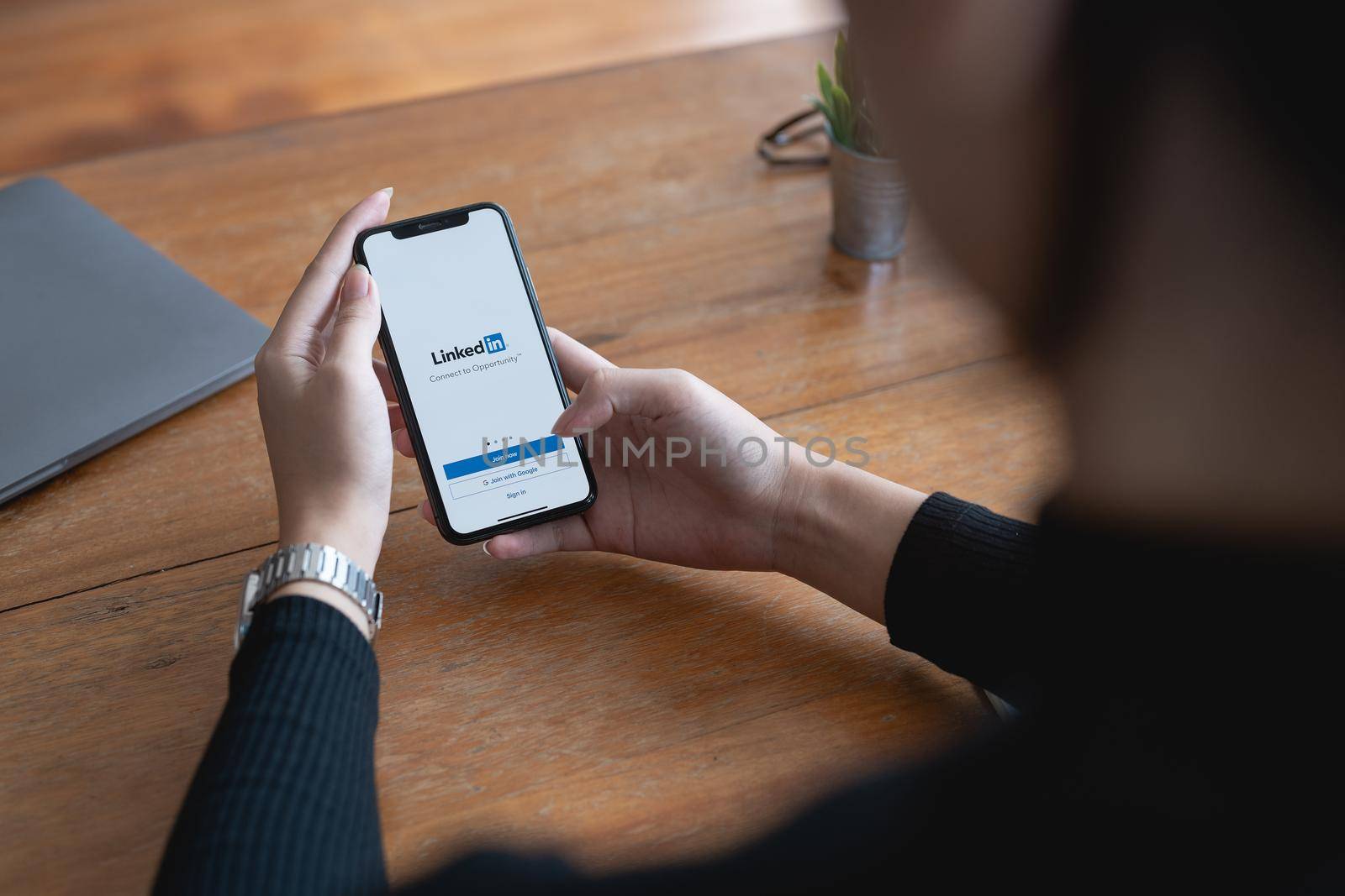 CHIANG MAI,THAILAND - JUNE 29, 2022 : Woman holding iPhone opening Linkedin app. Linkedin is social media website specialized in business networking. Illustrative editorial