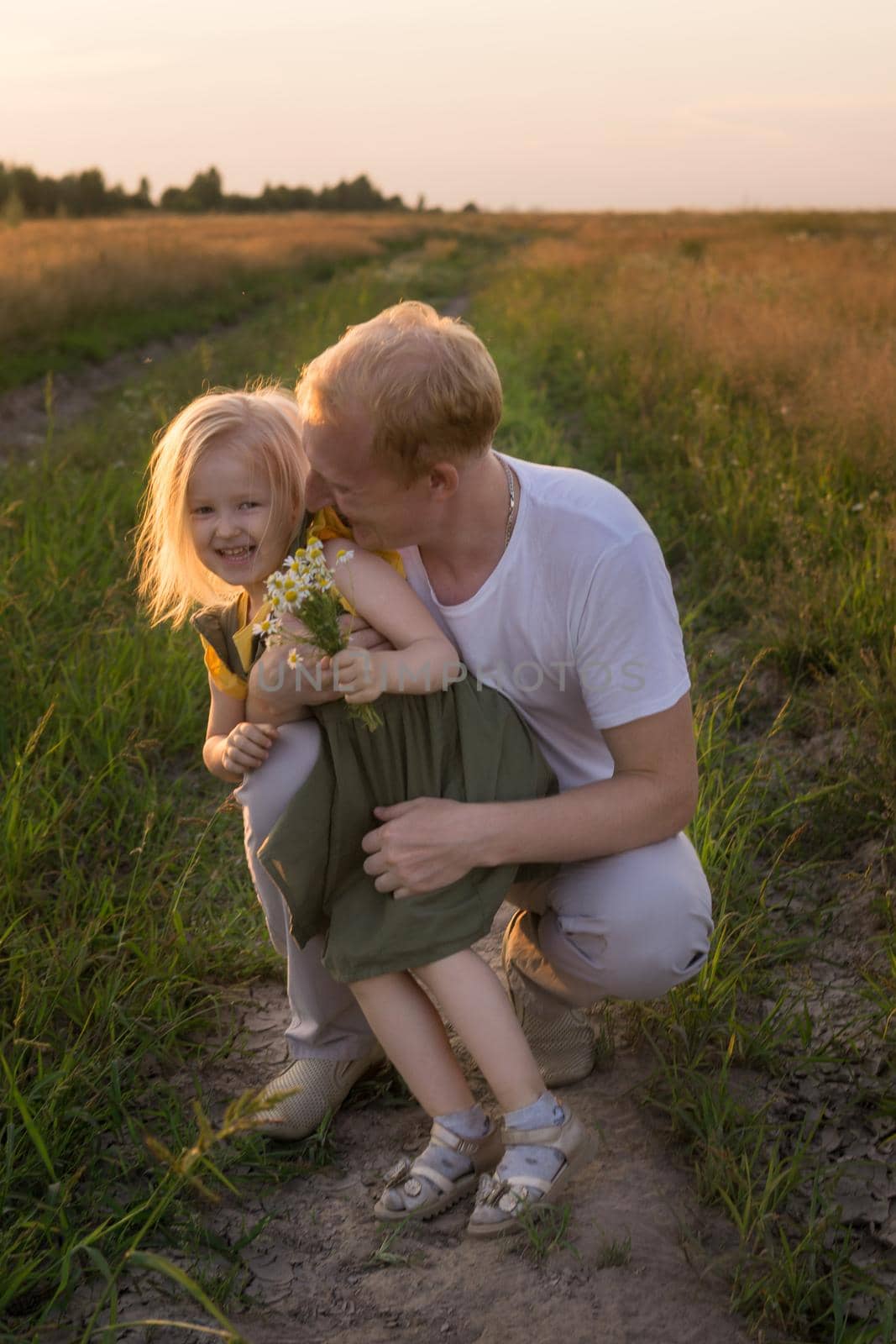 Dad and his blonde daughter are walking and having fun in a chamomile field. by Annu1tochka