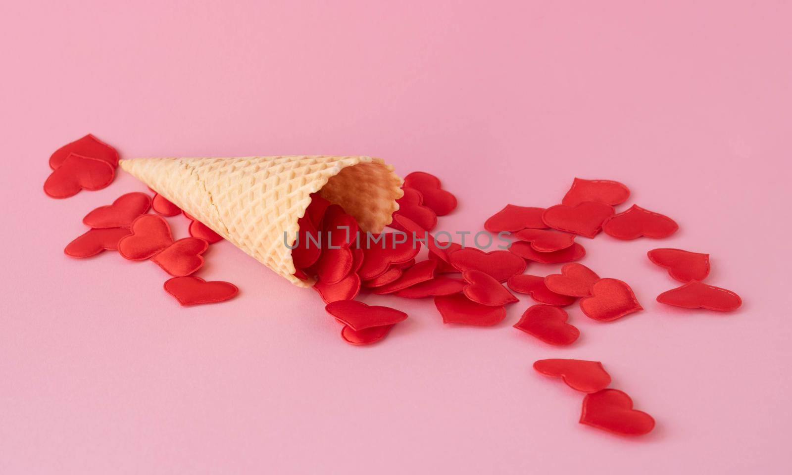 Creative photo of empty waffle cones with scattered red hearts on a pink background. The concept of love, summer, spring by lapushka62