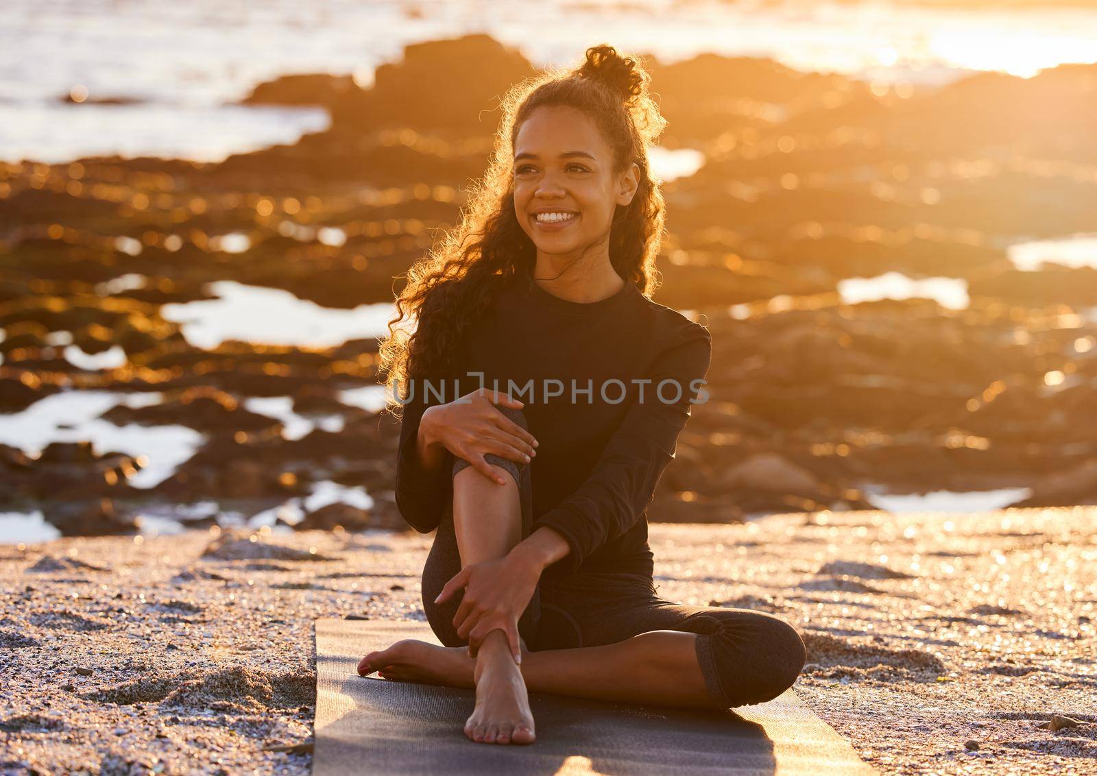 Yoga is the practice of being present in every moment. an attractive young woman sitting on her yoga mat during a yoga session on the beach at sunset