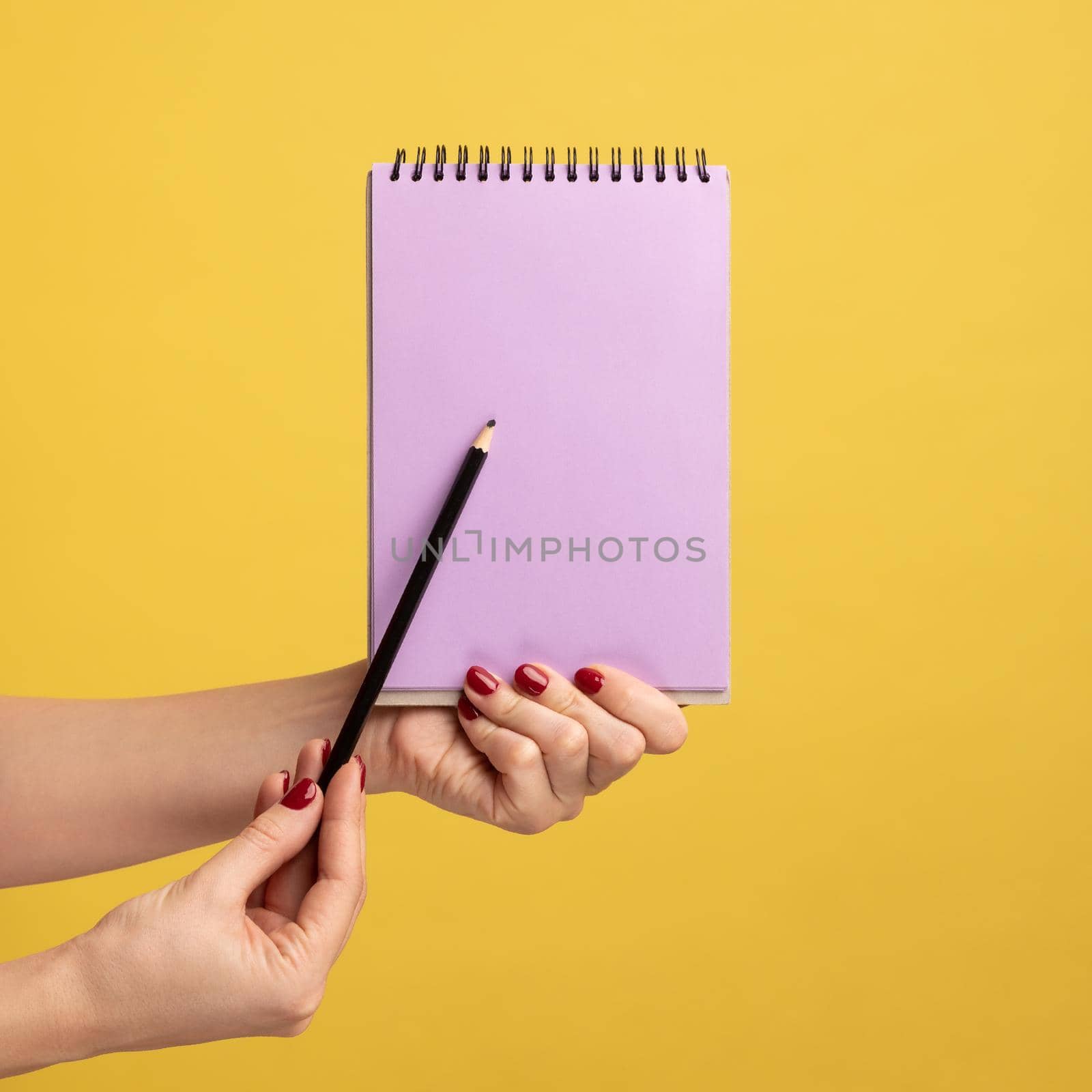 Woman hand holding purple notepad in hand and showing empty paper with pen or pencil. by Khosro1