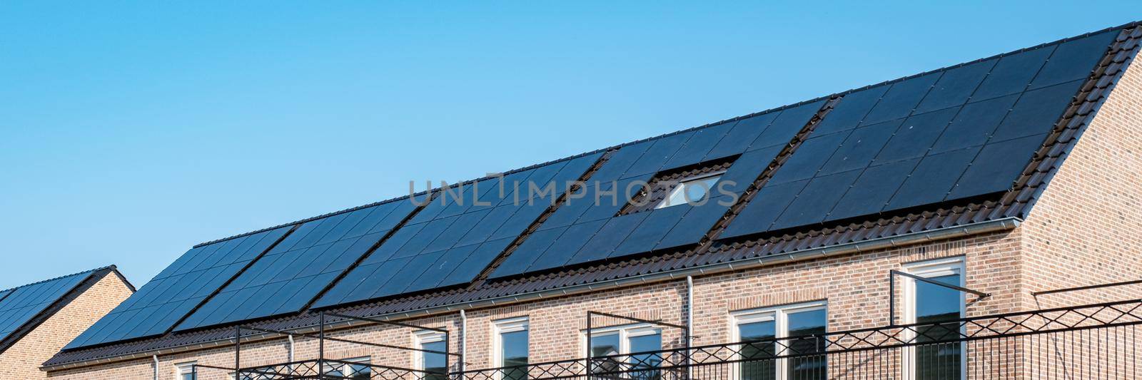 Newly build houses with solar panels attached on roof against a sunny sky Close up of solar pannel by fokkebok