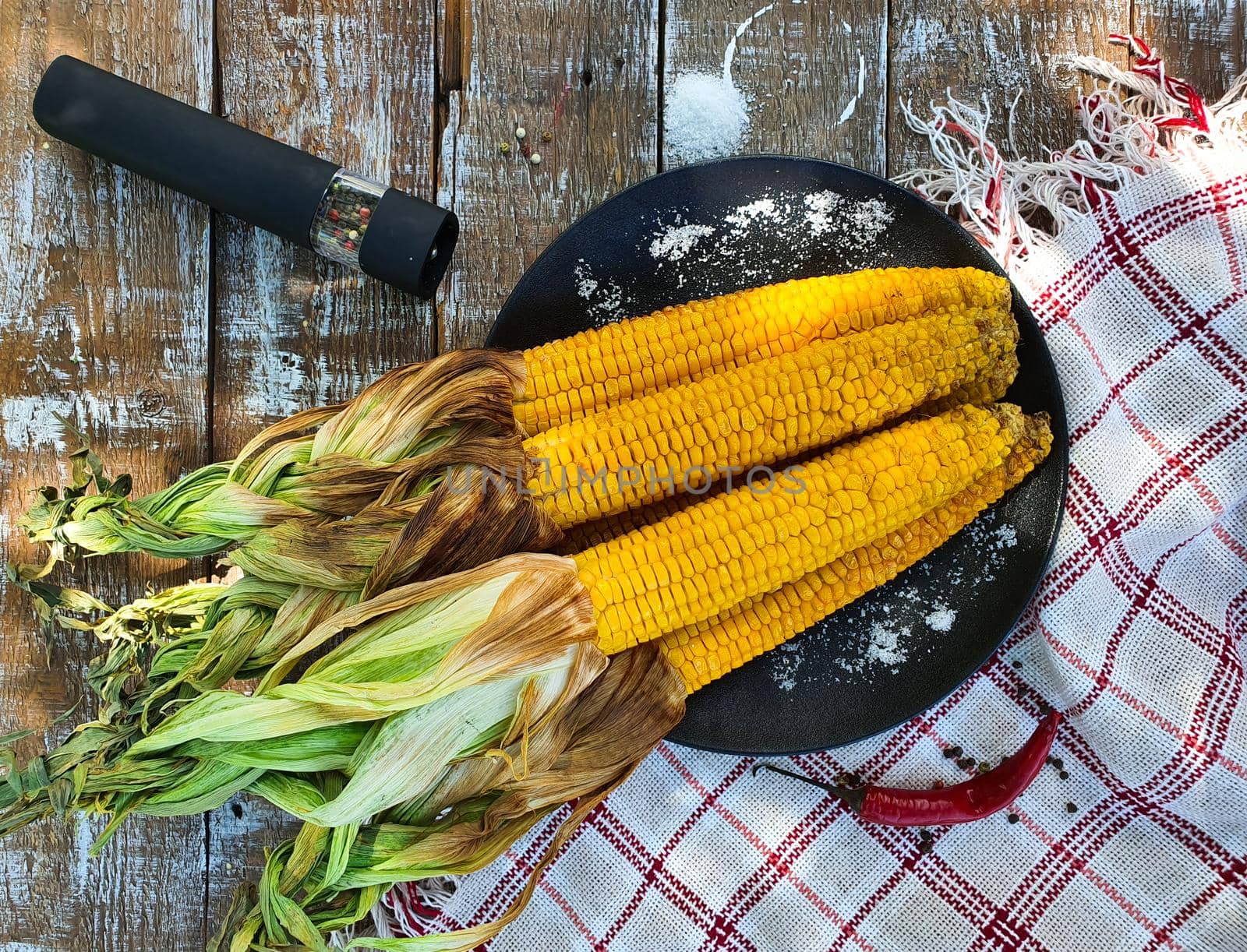 There is grilled corn on a black plate. High quality photo