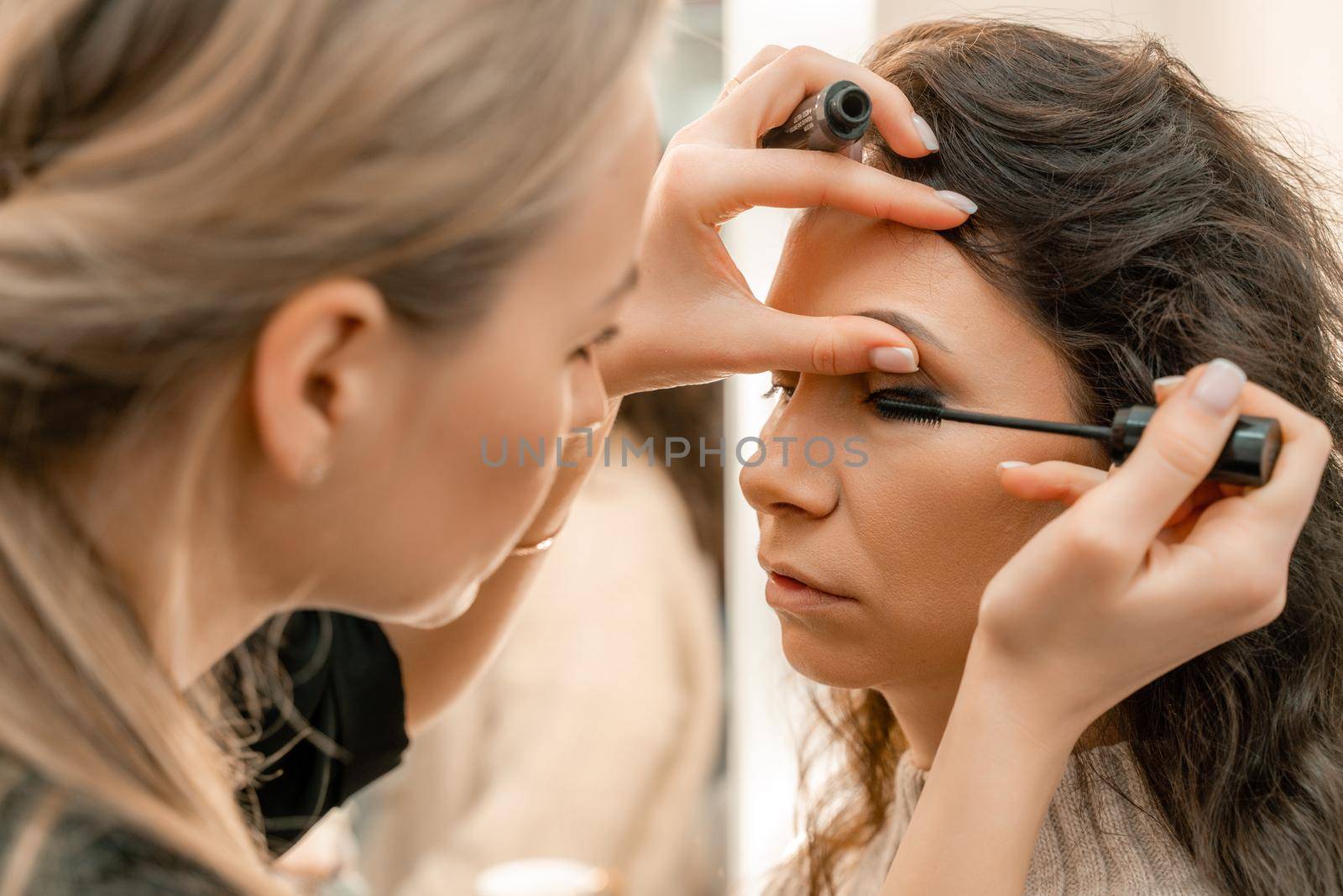 Make-up artist makes a professional make-up of a young woman in the studio