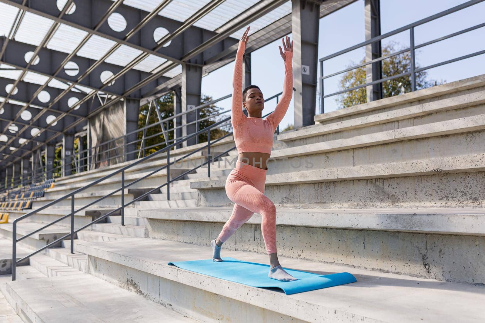 African American woman doing yoga near the stadium in the morning, active lifestyle performs fitness exercises