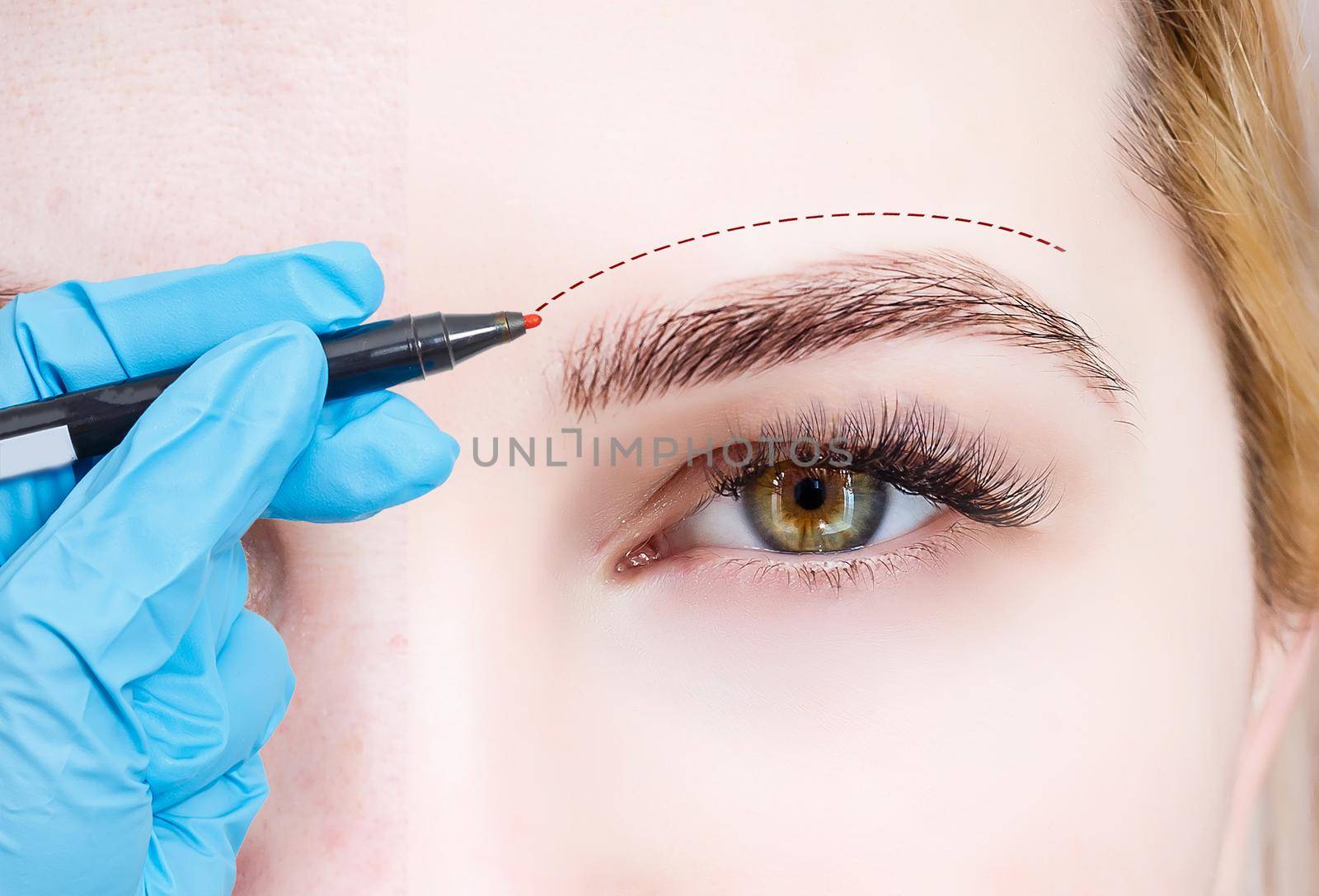 Plastic surgeon drawing dashed line under eye of girl. Hand in blue glove holding pencil. Plastic surgery, beauty portrait, closeup
