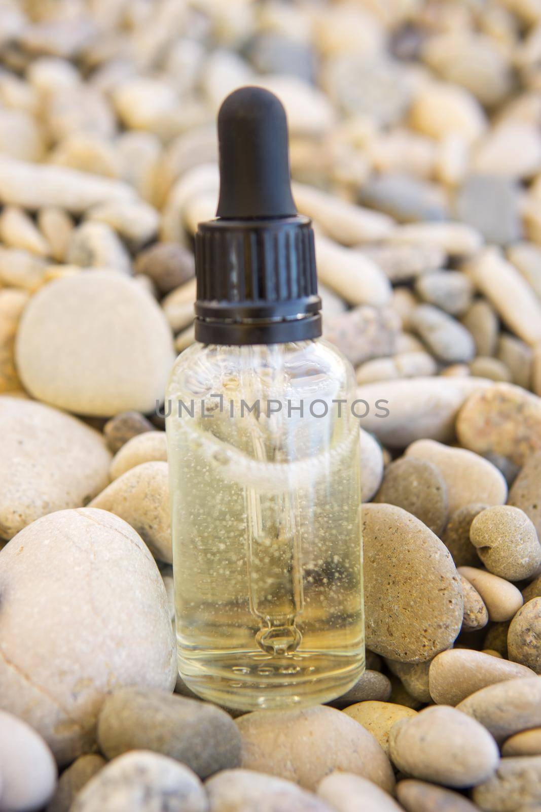 Cosmetic serum in a glass bottle with a pipette on stones by Annu1tochka