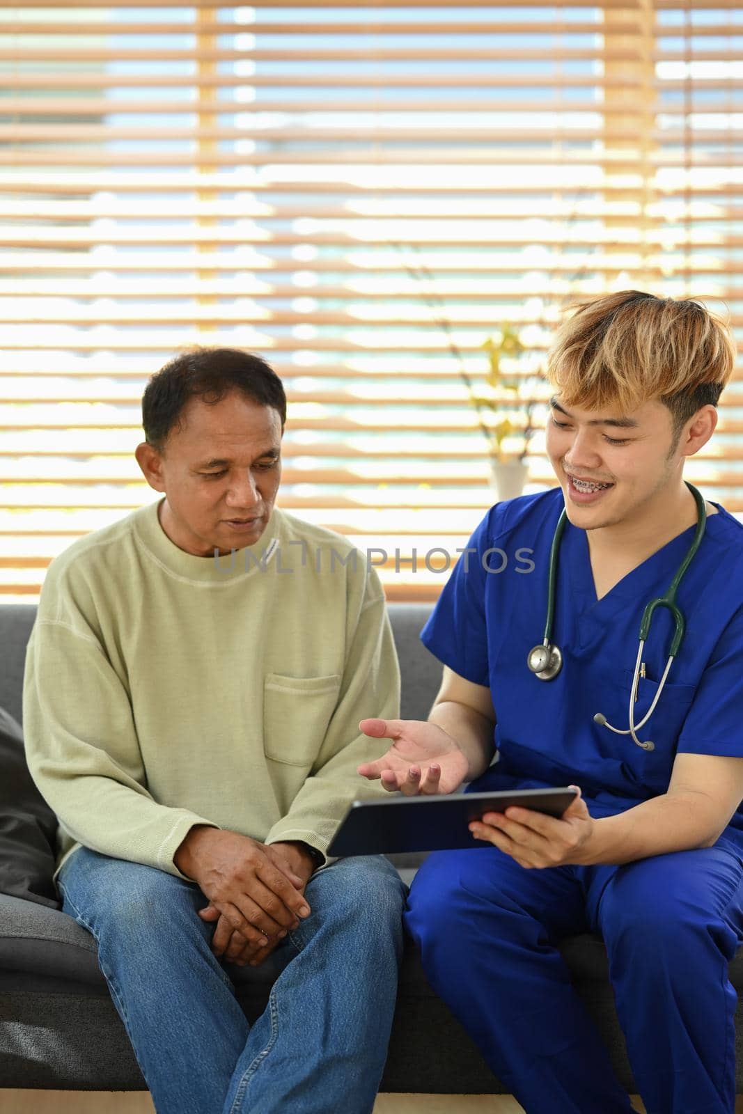 Smiling asian doctor talking and explaining test result to elderly patient during home visit. Elderly healthcare concept by prathanchorruangsak